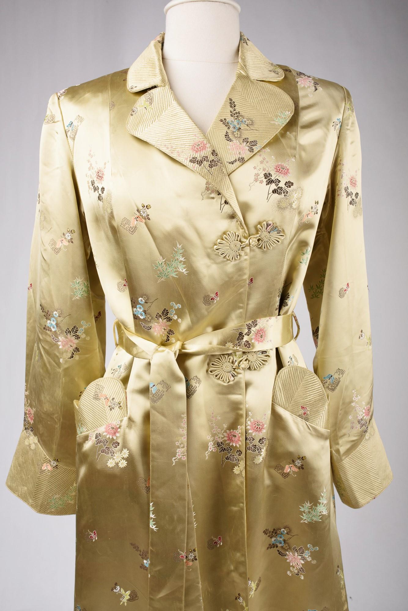 Vers 1940-1950

Chine pour l'exportation vers l'Europe

Magnifique robe de soirée des années 1940 en satin de soie jaune paille brillant, brodée d'un motif de fleurs japonaises. Manteau ample, croisé sur le devant et fermé par des clochettes en