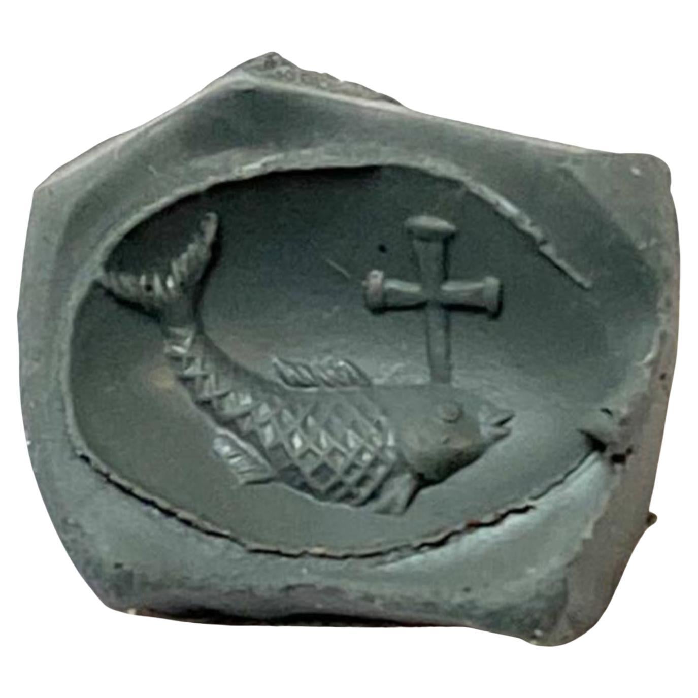 Ein großer Goldring mit einer Inschrift, die einen Fisch zeigt, der nach links schwimmt und aus dessen Kopf ein Kreuz entspringt. Dieses Intaglio zeigt eine ungewöhnliche Darstellung des 
