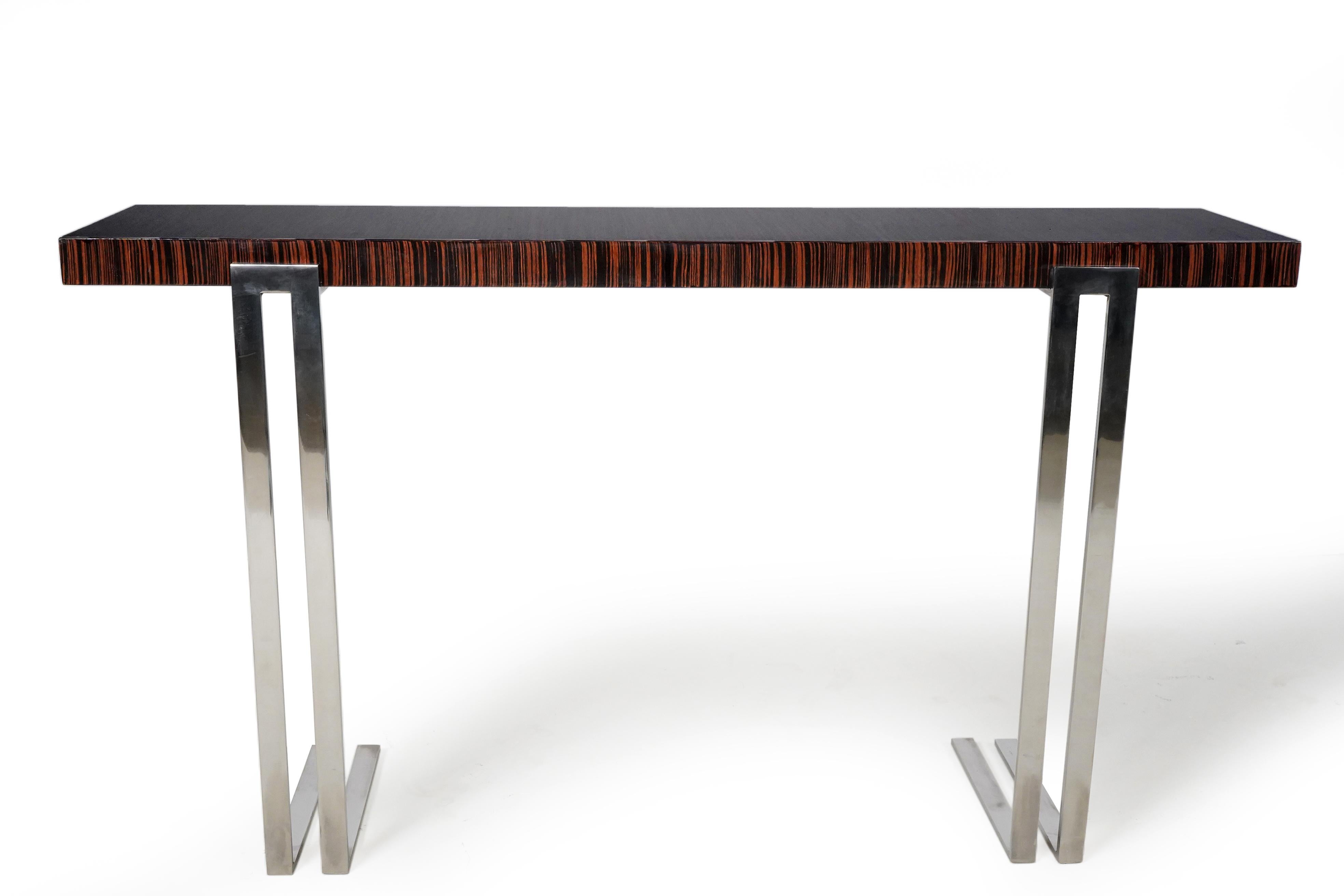 This slim console table features flawless palisander veneer laid front-to-back for artistic effect. The top slab is mounted on solid steel legs that are chrome-plated. The piece is fitted with clips on the back that attach to the wall. Without rear