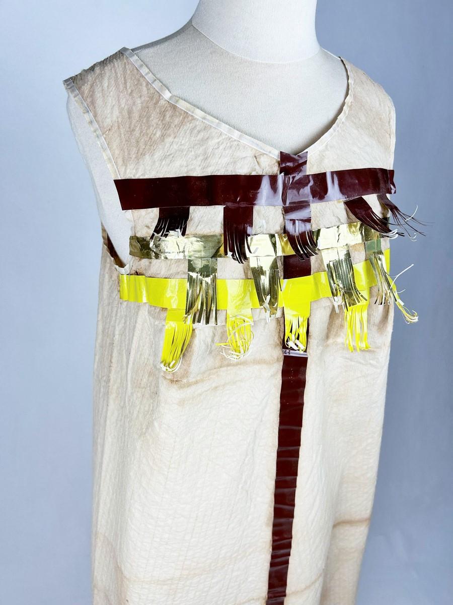 Circa 1967

Francia

Abito di carta gadget creato a Roanne da Anik Robelin per Paco Rabanne. Abito lungo senza maniche applicato con nastro adesivo marrone, giallo e oro con frange. Premi le linguette dei perni sulle spalle. Inizialmente un abito