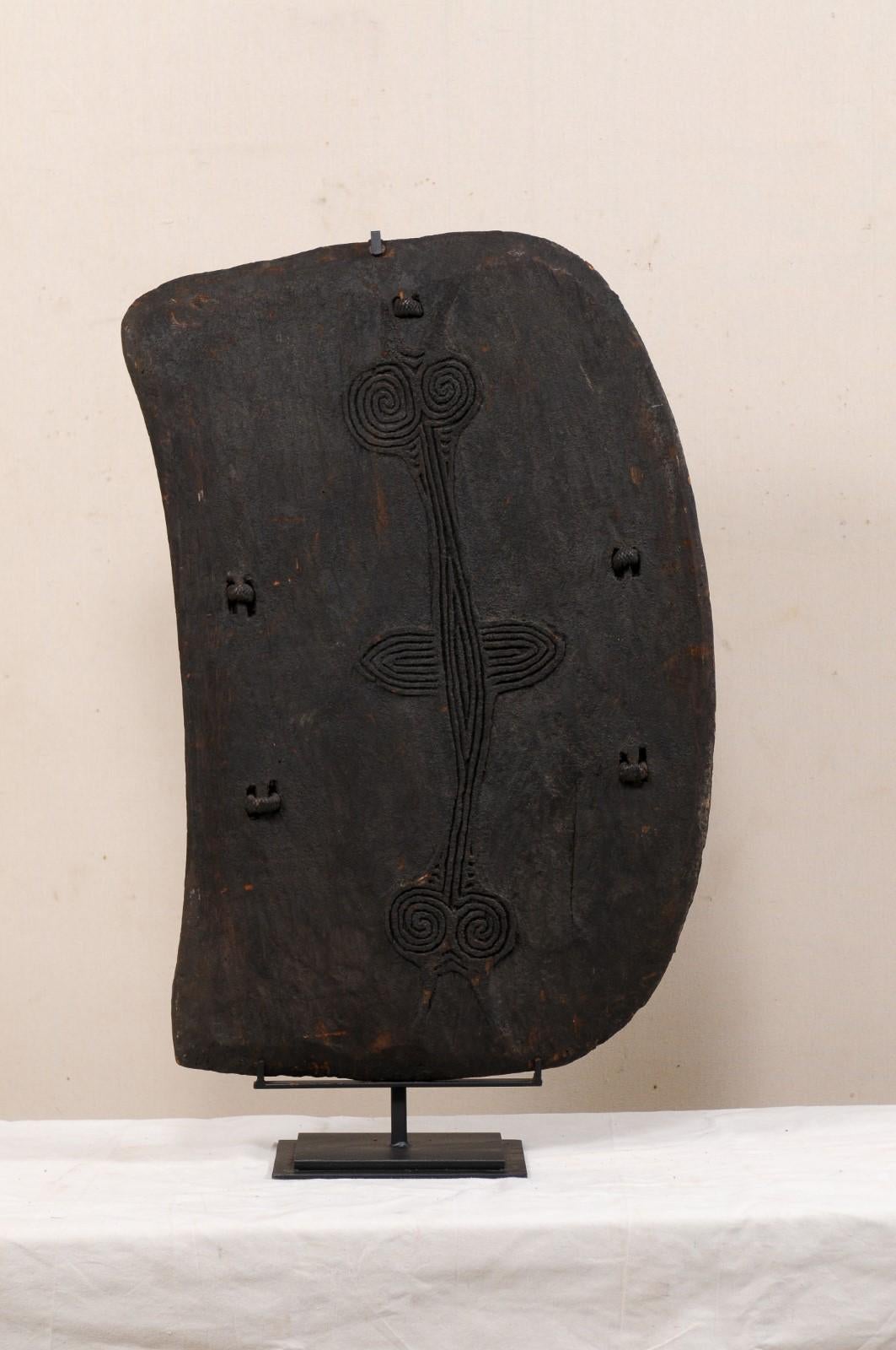 A Papua New Guinea carved-wood Lumi shield from the mid-20th century. This vintage war shield from the West Sepik region, the northwestern most province of Papua New Guinea (now referred to as Sandaun Province), features the typical kidney-shaped