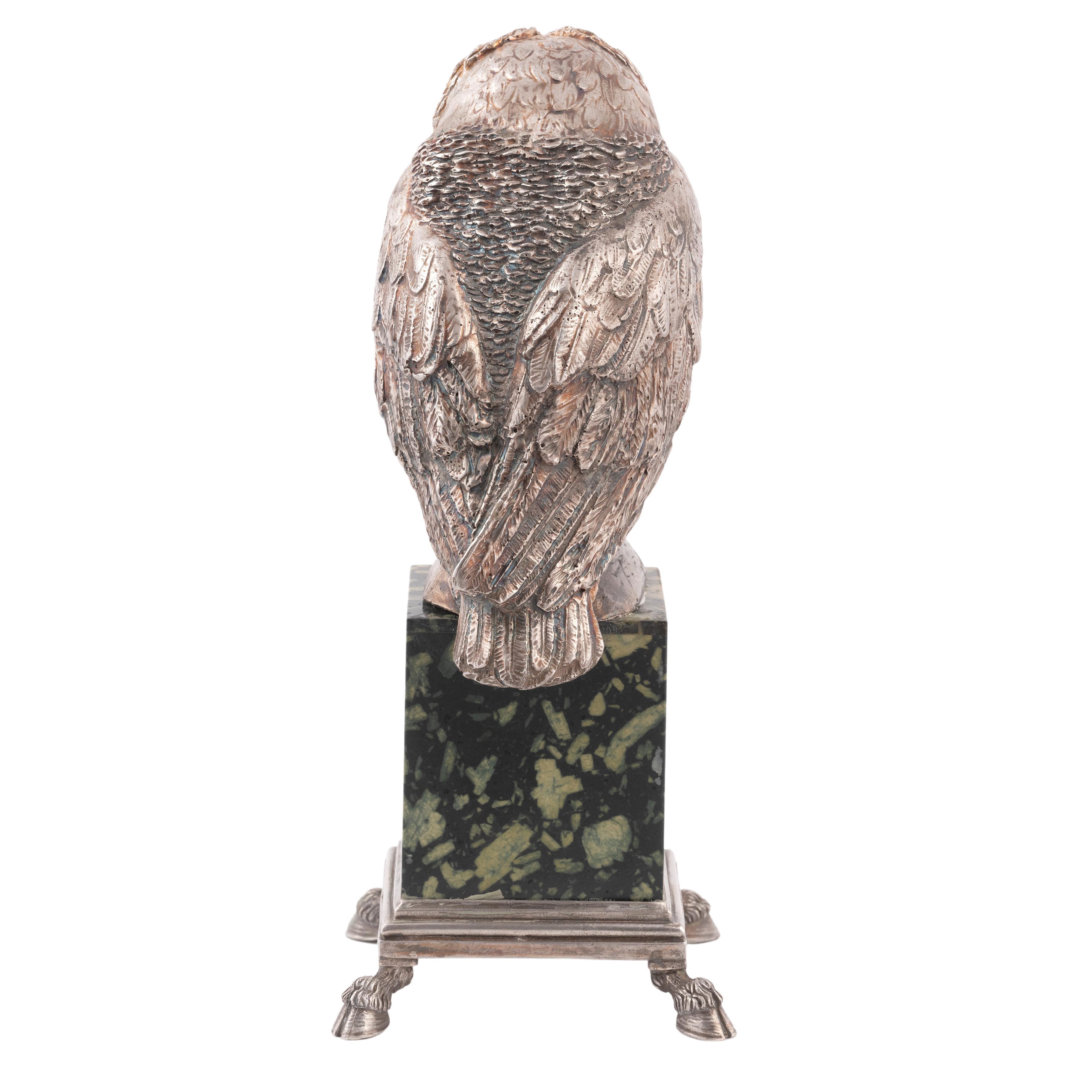 A parcel-gilt silver ornament modelled as an owl on marble base.
With Italian maker marks circa 1890's
With glass eyes and feather-effect texturing, height 28cm,