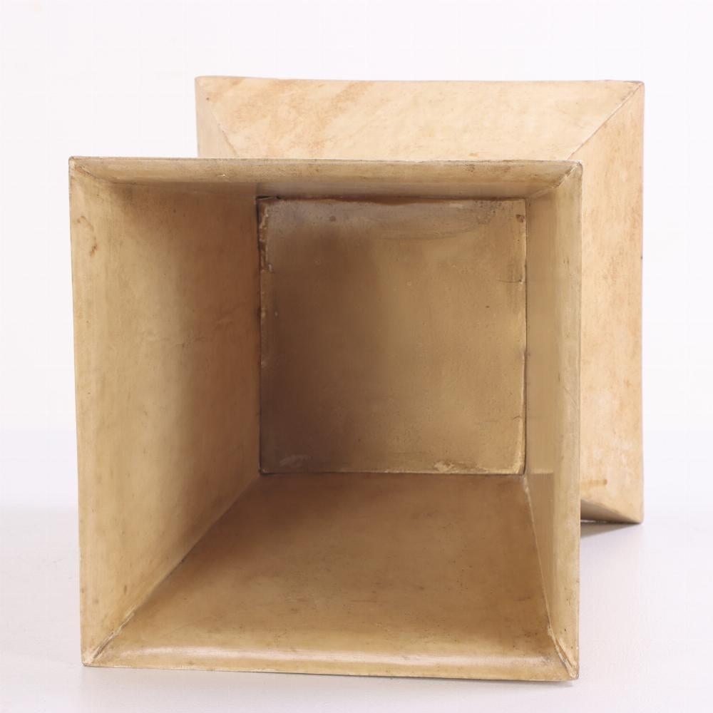 Der Korb hat eine skulpturale, geometrische Silhouette und ist mit handgefärbtem Pergament umwickelt. Das kantige Design verleiht Ihrer Einrichtung einen architektonischen Akzent, während die Pergamentoberfläche eine weiche, organische Textur mit