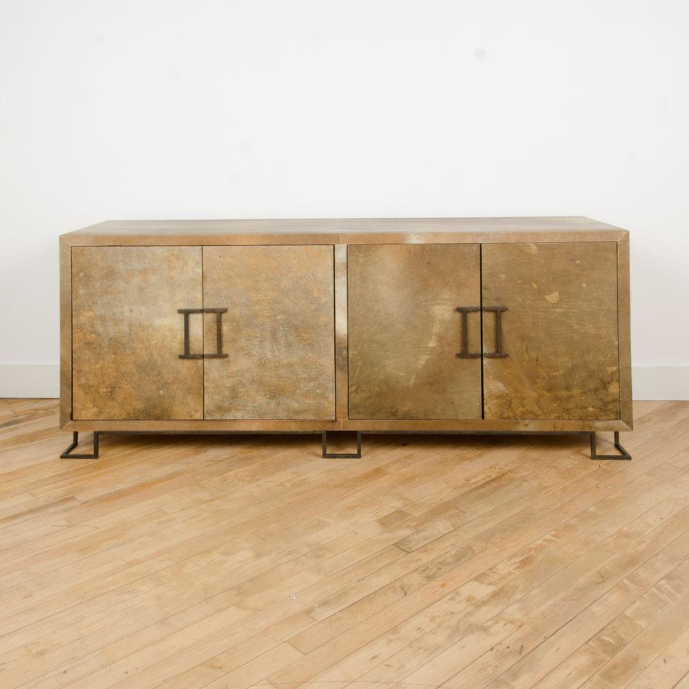 A parchment four door credenza with iron feet and hardware in the manner of James Mont. Contemporary.