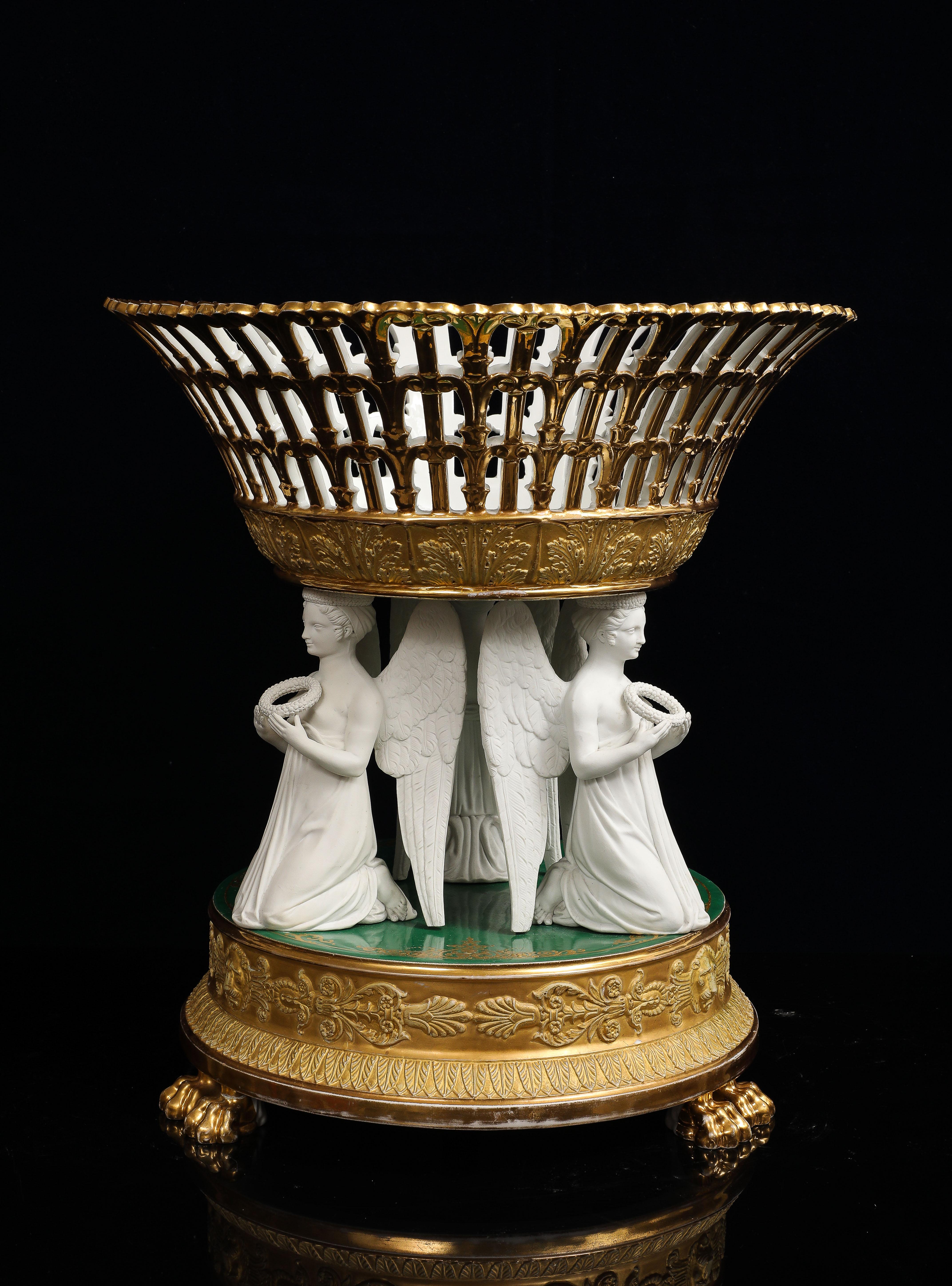 Centre de table réticulé en biscuit de porcelaine de Paris, doré et vert, du 19e siècle. La pièce présente quatre figures féminines ailées agenouillées, modelées en biscuit de porcelaine blanche non émaillée, tenant chacune une couronne de laurier