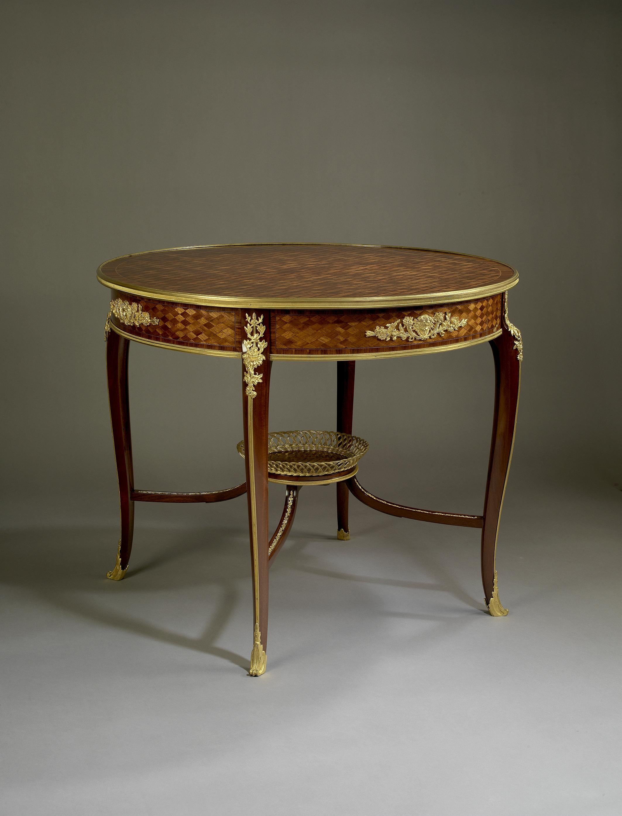 A gilt-bronze mounted parquetry inlaid centre table, Attributed to François Linke.

French, circa 1900.

The circular parquetry top of diapered trellis with gilt-bronze edging above a similar frieze with finely cast gilt bronze mounts of female