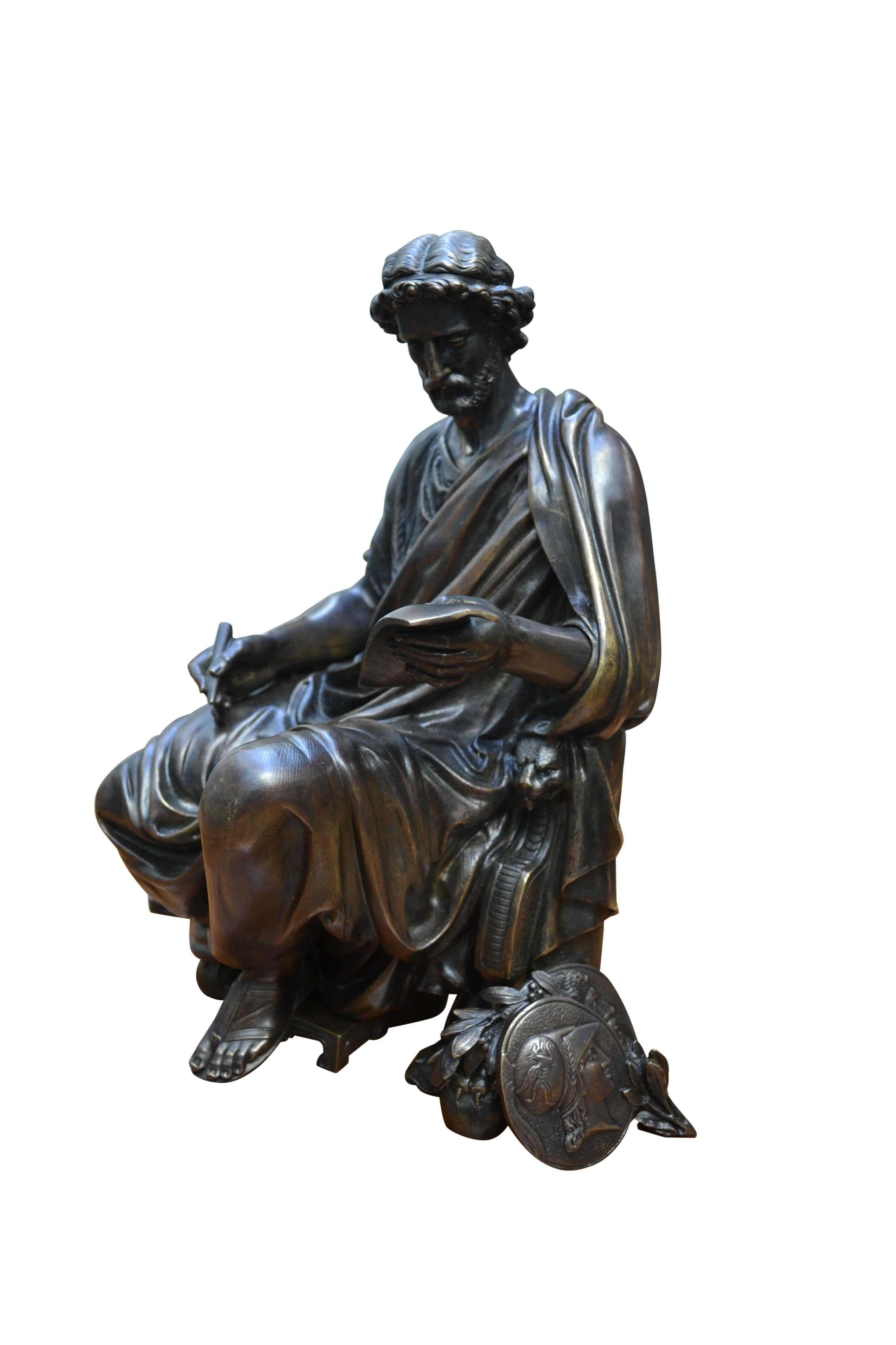 Patinierte Bronzeguss-Statue eines klassisch drapierten griechischen Gelehrten im Schneidersitz  auf einem Klismos-Stuhl  mit den charakteristischen Griffeln als vordere Beinstützen, das Motiv hält in der rechten Hand einen Stift und in der anderen