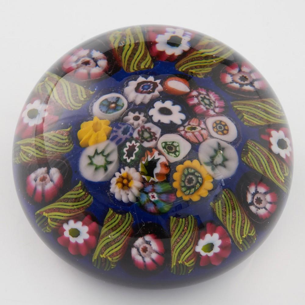 Heading : A Paul Ysart Close Packed Concentric Radial Paperweight c1950
Date : c1950
Origin : Scotland
Features : Closepack polychrome central canes with outer ring of ten radial twists interspersed with a single cane on a blue ground
Marks :