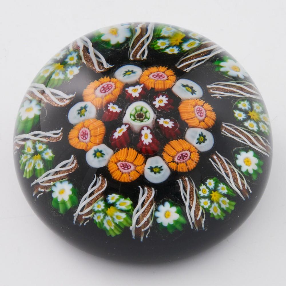 A Paul Ysart Concentric Millefiori Paperweight, c1950

Additional information:
Date : c1950
Origin : Scotland
Features : A two ring concentric centre with outer ring of twelve aventurine radial twists interspersed with single canes
Marks : none
Type