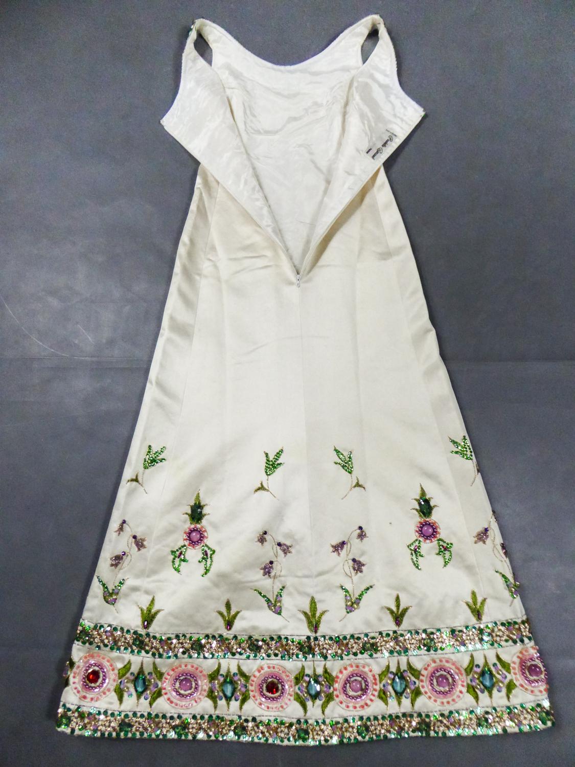 Circa 1968
France

Dress in cream silk satin richly embroidered signed by Paulette Buraud from the late 1960s. Impressive embroidery on the collar and bottom of the skirt, with green, purple, gold spangles and sequins, colorful pearls and