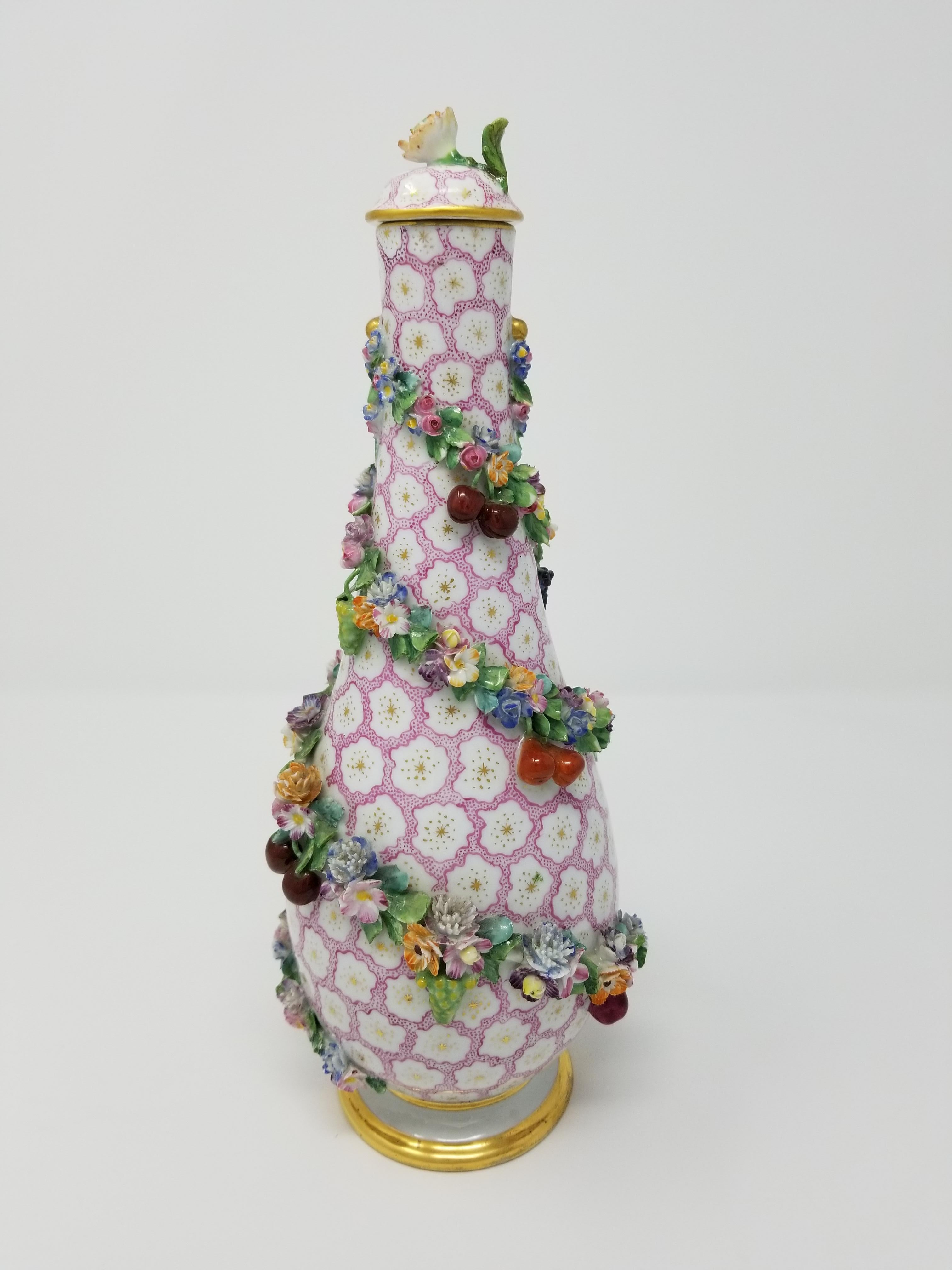 A beautiful early 19th century pear shaped Meissen covered vase with raised fruits, vines and flowers. The vase is finely hand painted with pink and white flowers. The rim and base of the vase are highlighted with 24-karat brushed gold and the pink
