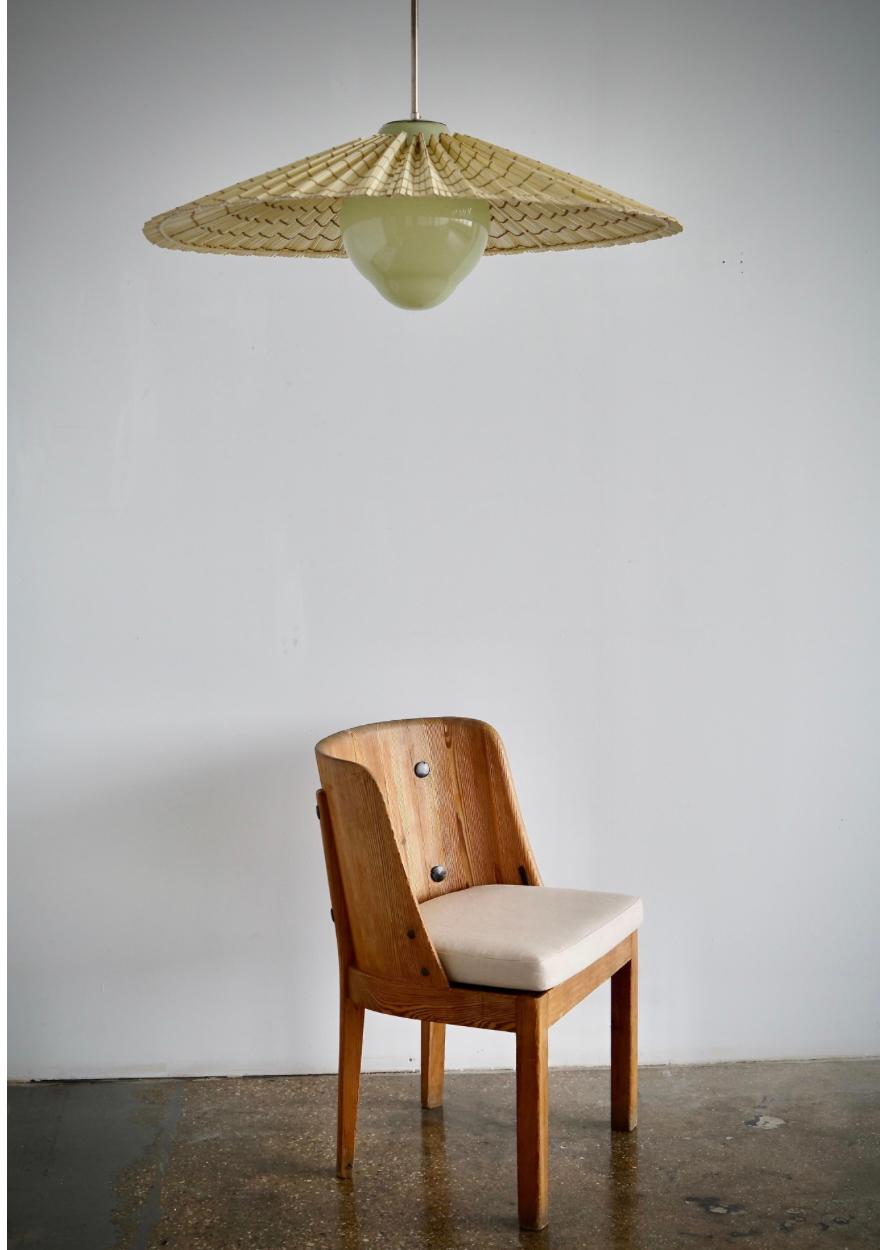 Un ciondolo progettato da Paavo Tynell per Taito OY, Finlandia, modello 1092 del 1940 circa.
Vetro color pistacchio con paralume a doghe di Wood sbiancato.
Fili esistenti, ricablaggio disponibile su richiesta. H. 48″; Diam. 32″
