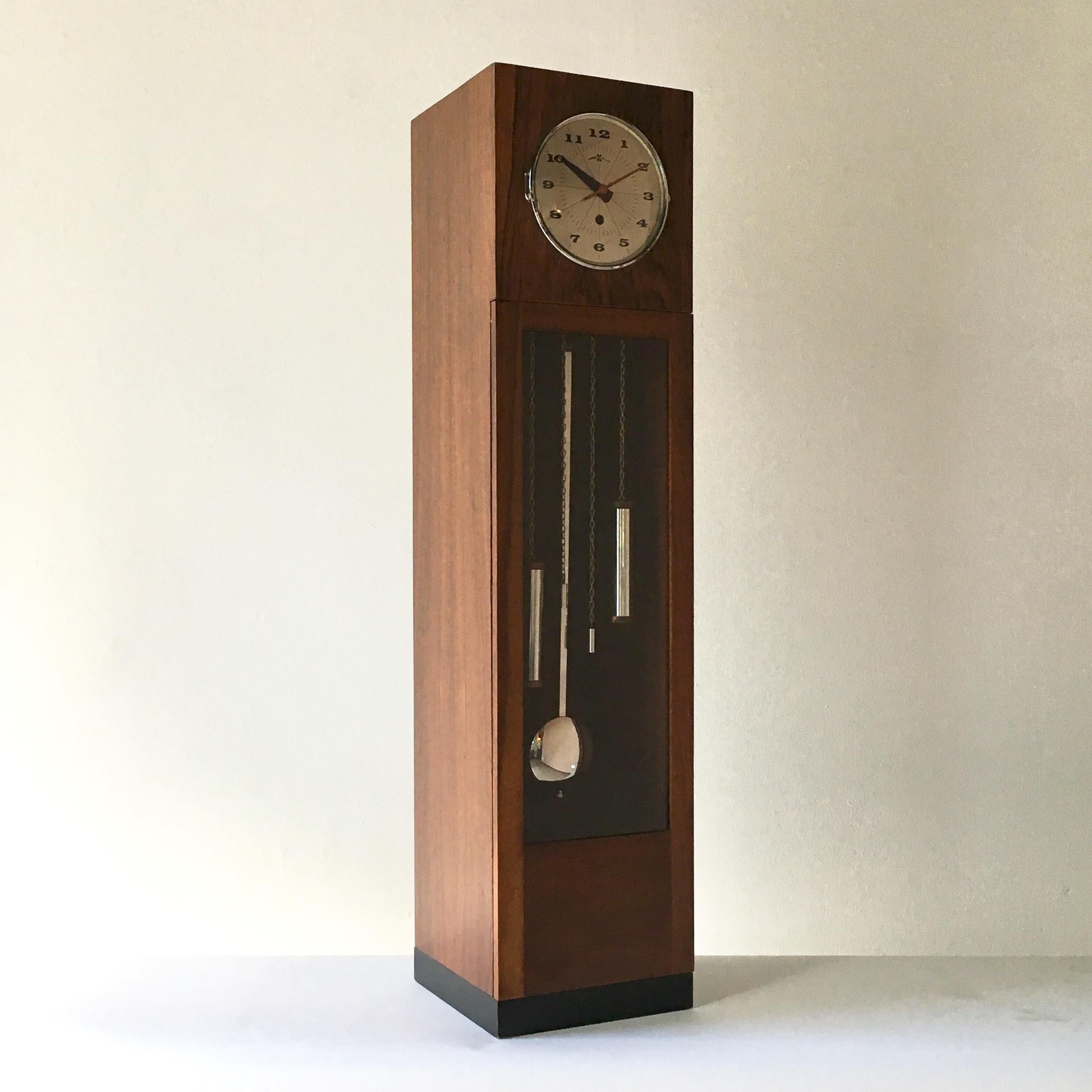 A miniature grandfather case clock designed by George Nelson for Howard Miller Clock Company, Zeeland, Michigan, 1960s, complete with pendulum and weights behind a glazed door, likewise with the clock face. 

Partial instructions on how to regulate