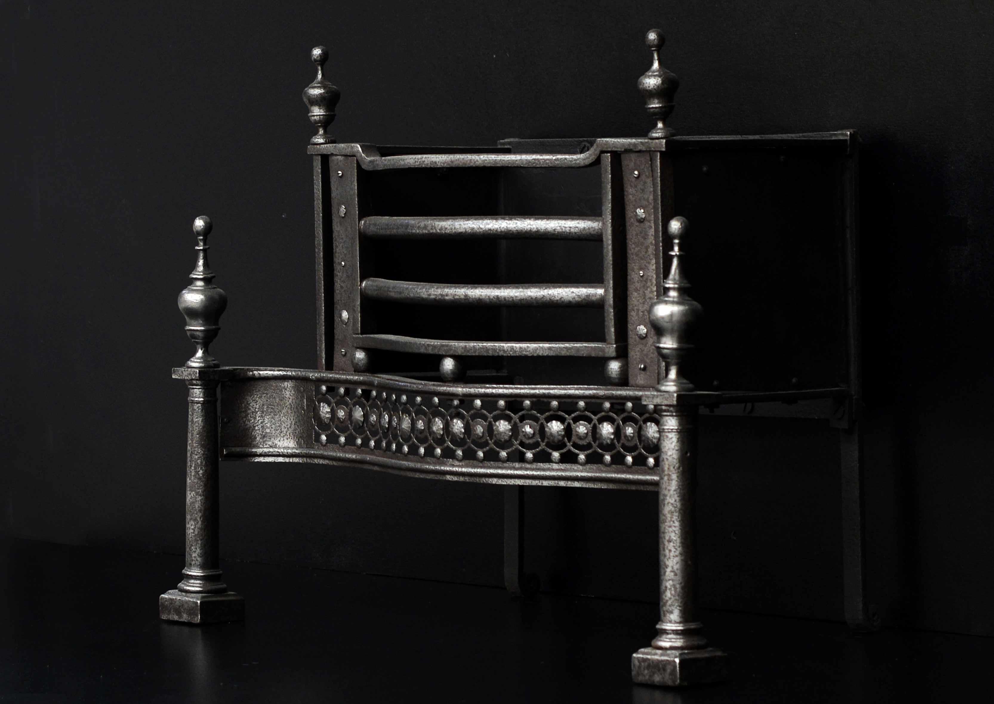 An English, mid 18th century polished steel firegrate. The pierced, guilloche fret with cut steel paterae and surmounted by shaped front bars above. The cylindrical legs surmounted by urn finials and shaped top bar. Wrought iron front panels and