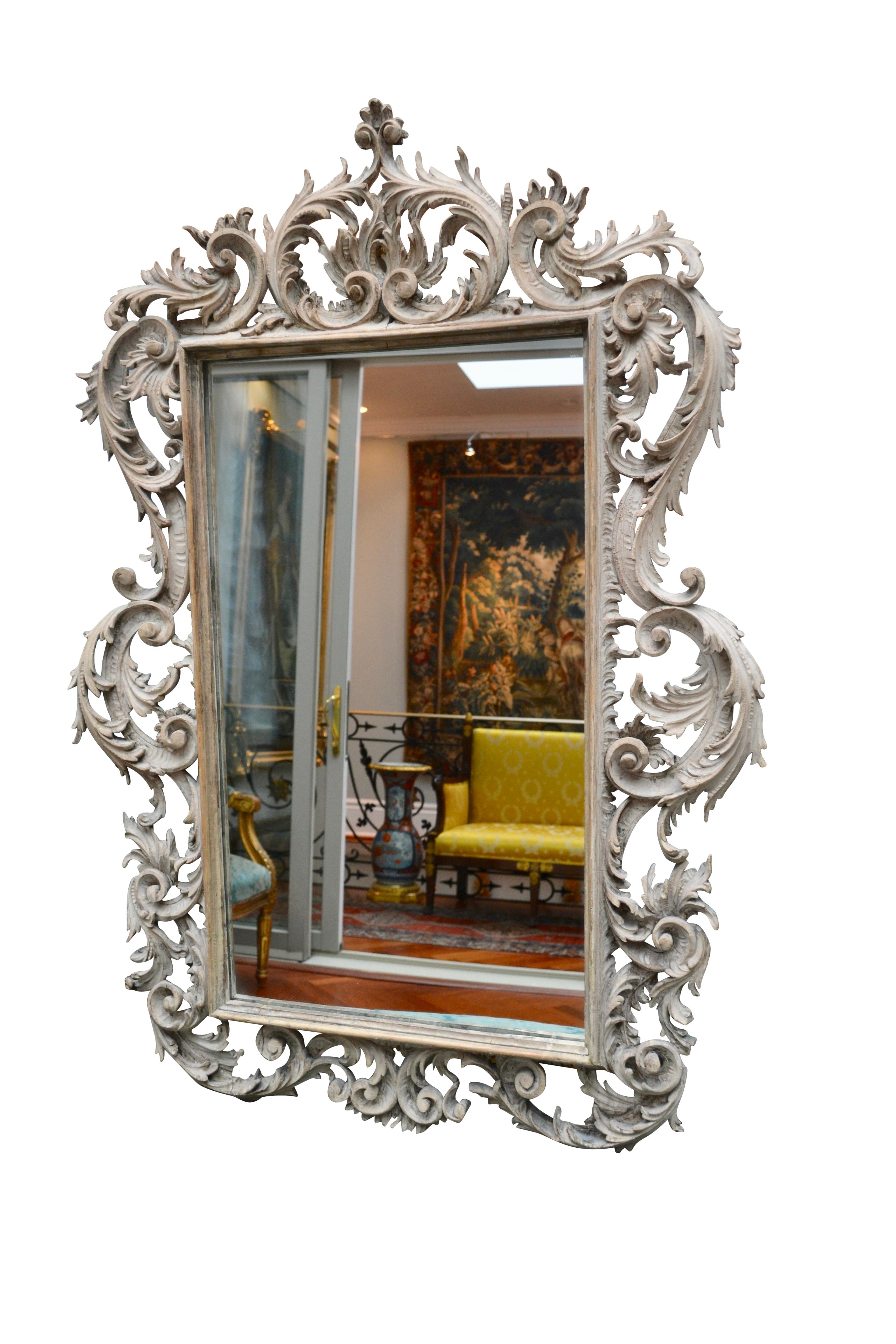A period George III carved and painted pine mirror. The rectangular mirror plate within a carved and moulded cartouche frame in the full Rococo manner of Thomas Chippendale, with stylized acanthus, rocaille and ‘C’ scroll decoration.

