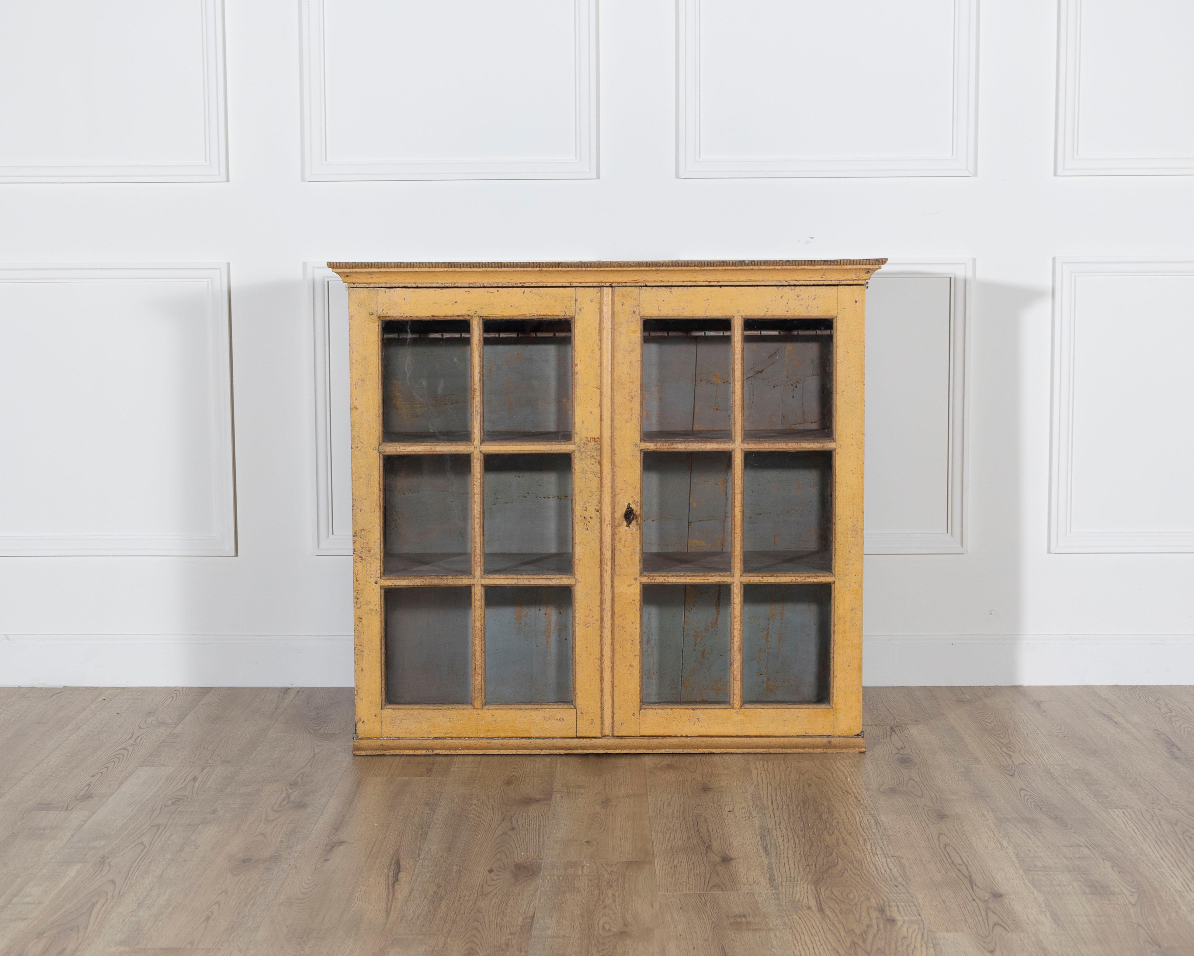 An authentic Gustavian period wall cabinet from Sweden, late 18th century, retaining its remarkable original surface and timeworn patina. The cabinet features a simple rectangular form with two glazed doors, each framed with wooden mullions that