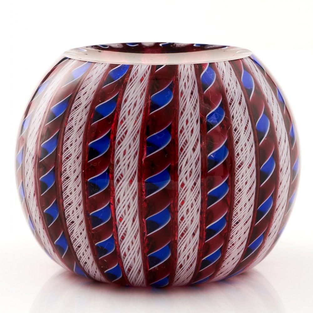 A Perthshire Crown Paperweight, 1996

Additional information:
Date : 1996
Origin : Scotland
Features : Red and blue twists alternating with white latticino rods on a ruby ground with a single flower visible from the top cut facet
Marks : A P1996