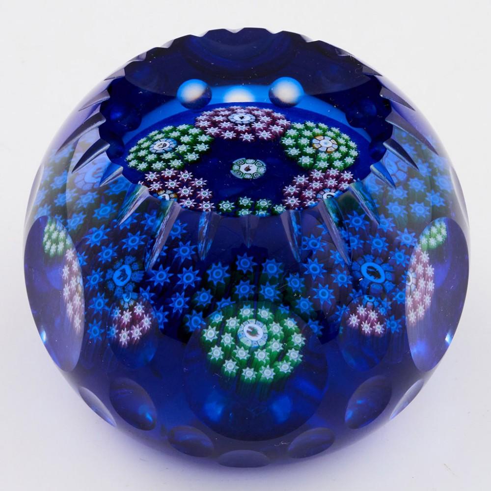 A Perthshire Overlayed Garland Art Institute of Chicago Paperweight, 1990's

Additional information:
Date : 1990's
Origin : Scotland
Features : A center coloured picture cane of a snail surrounded by six circlets each with a central picture cane