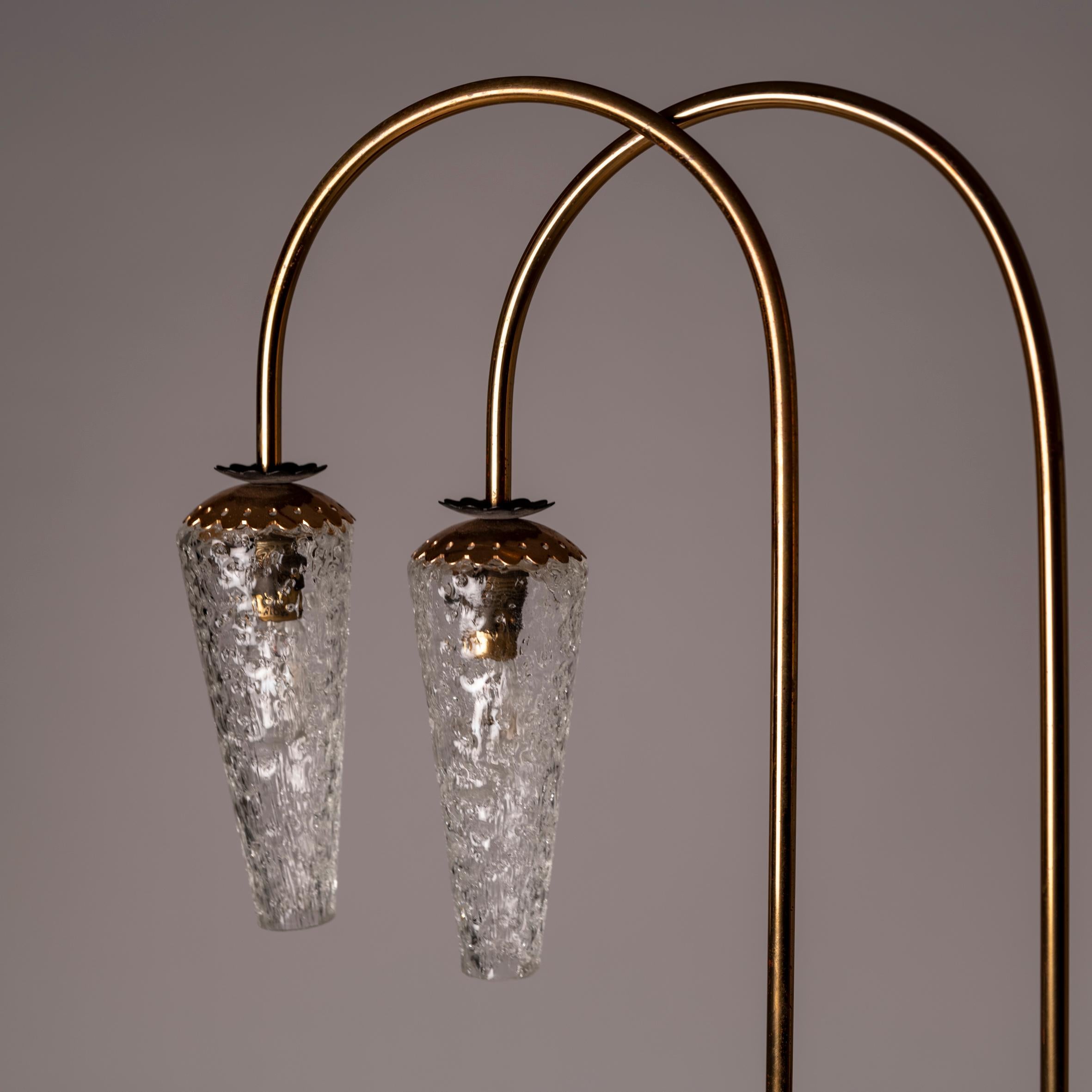 This Petit French brass and glass floor lamp attributed to Lunel from the 1950s is a compelling choice for those seeking to elevate their interior with timeless elegance and understated sophistication. The combination of brass and glass exudes a