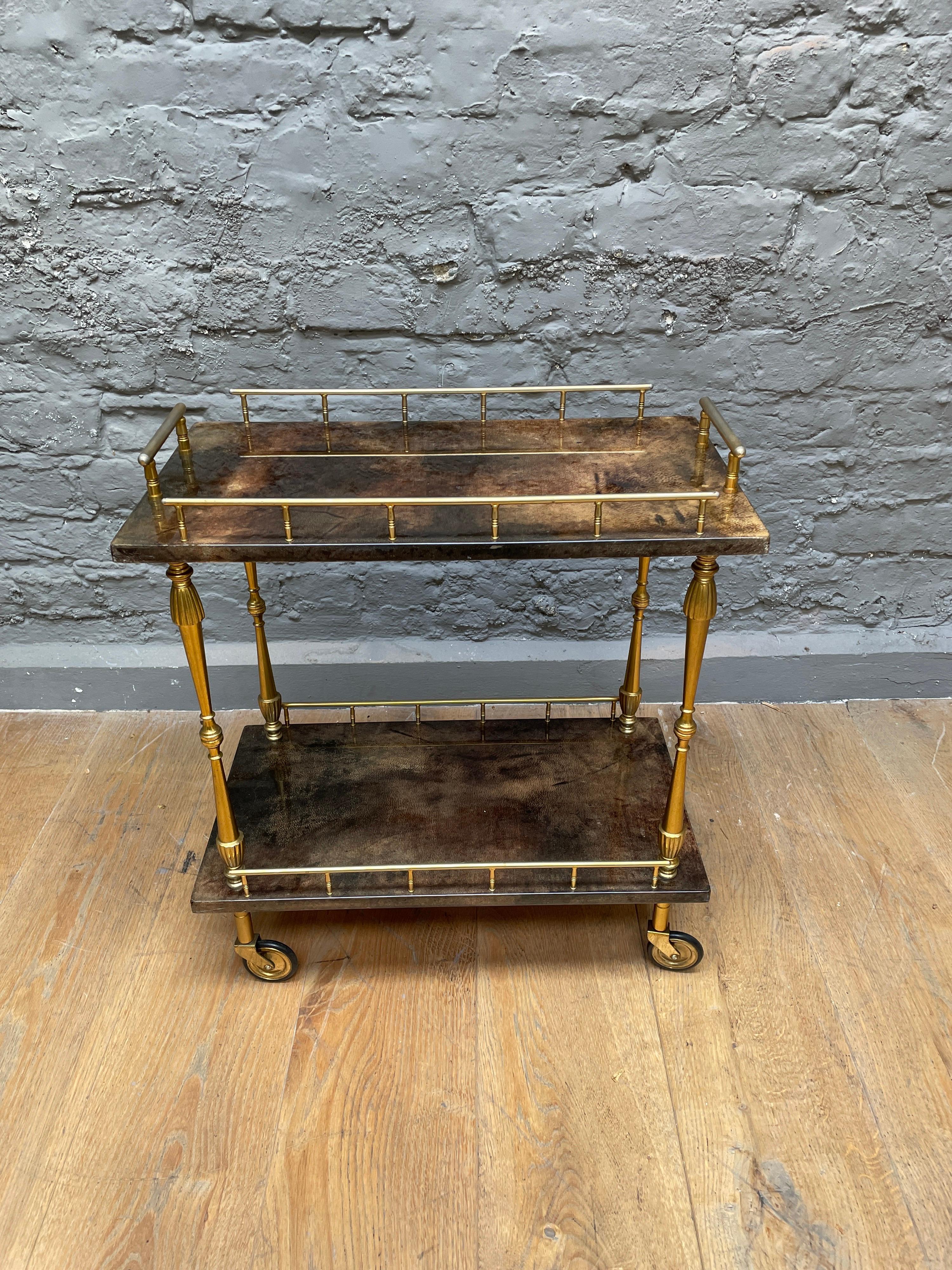 A compact two tiered serving table by Aldo Tura, in dark lacquered goatskin and gilt brass.