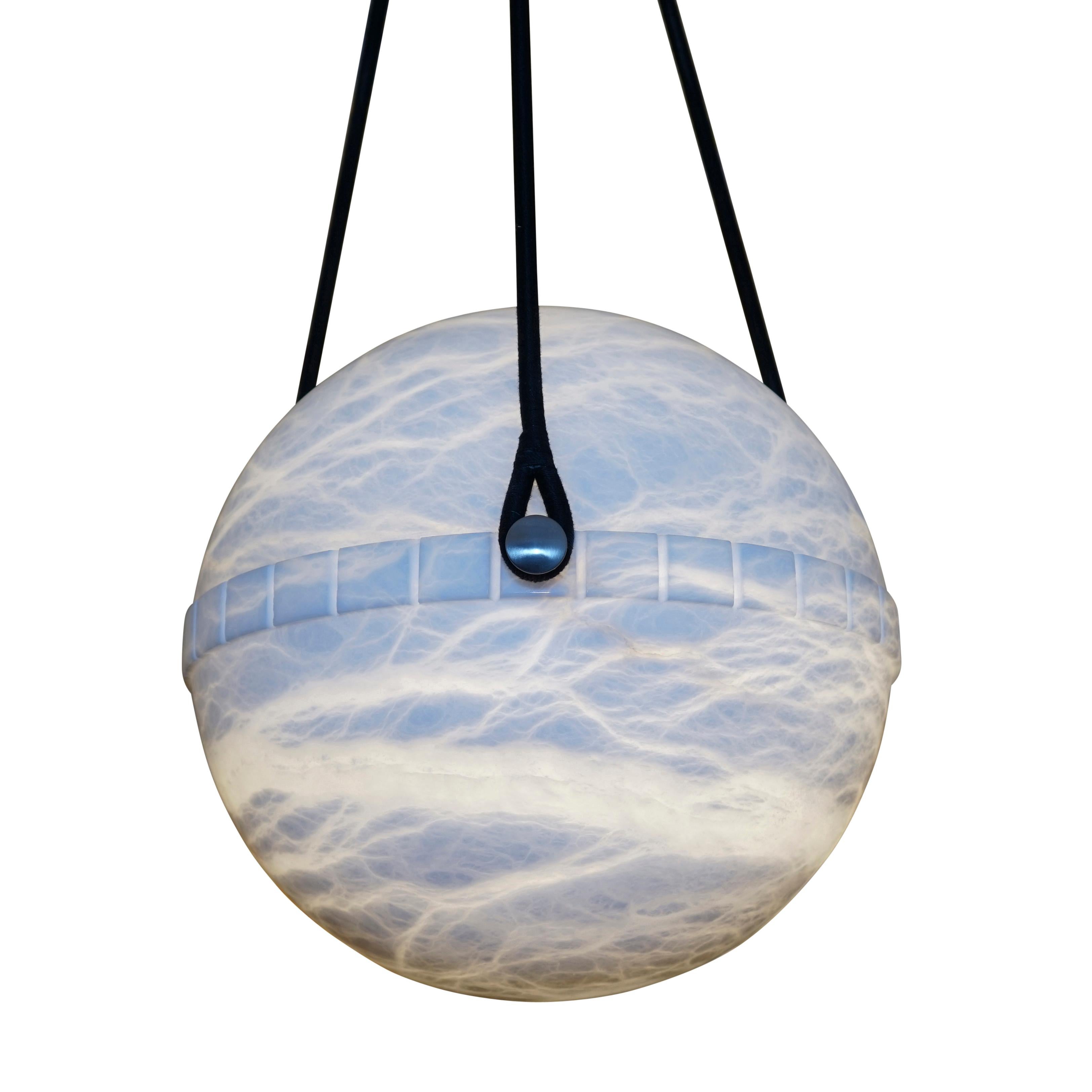 One of a pair; more unusual than the bowl shaped pendants, the globe alabaster features a lower half with a crisp dental motif on the central band and suspends on a set of three brushed nickel flattened balls. The upper half nestles perfectly into