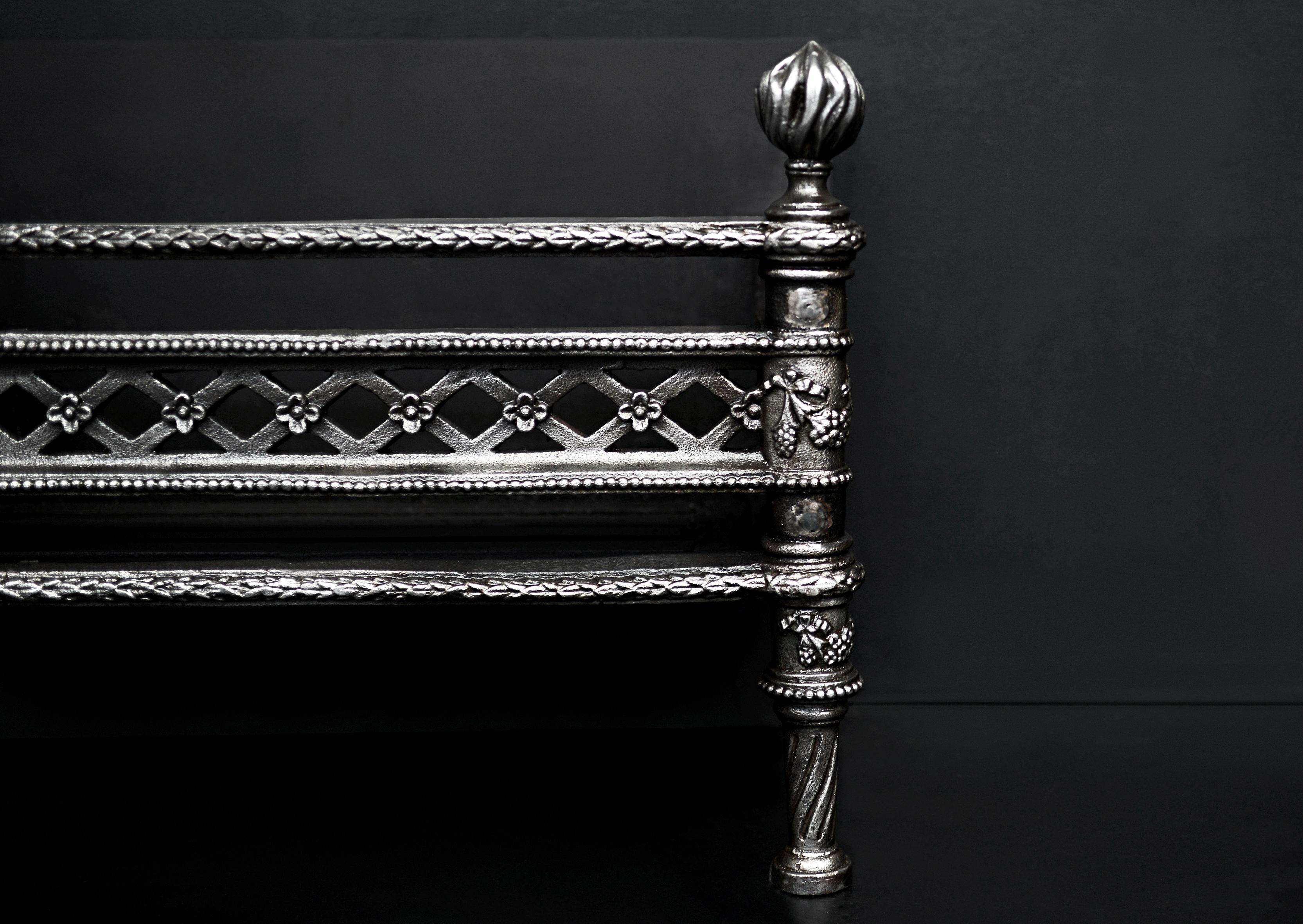 A decorative cast iron fire grate. The legs with beading, foliage, and fruit throughout, surmounted by flamed finals. Plain iron back behind. Modern.

Sizes:
Width at front 555 mm 21 7/8 in
Width at back 564 mm 22 1/4 in
Height 412 mm 16 1/4
