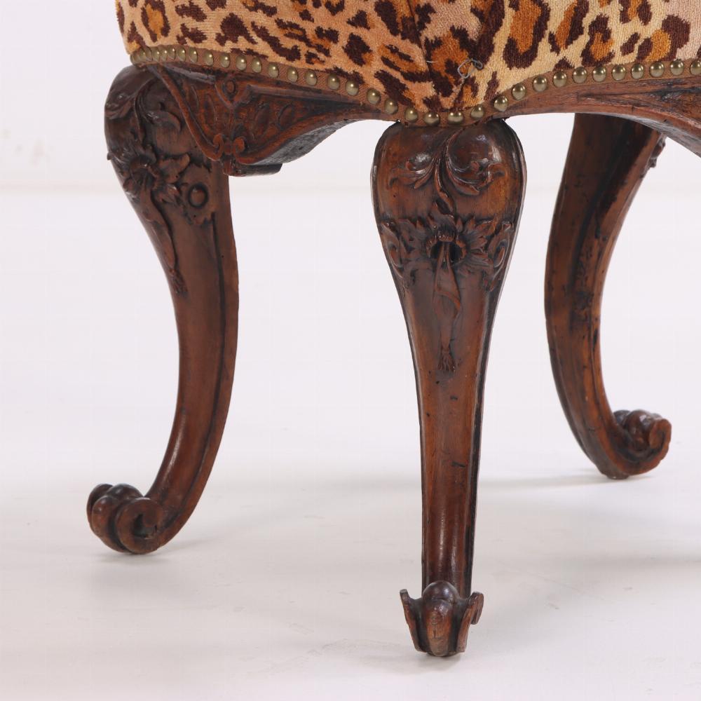 The stool is distinguished by a shaped apron, cabriole legs with floral-carved knees ending in scrolled feet, and the dramatic leopard print upholstery. 

Perfect for resting your feet in front of the fireplace or as a seat in front of your vanity