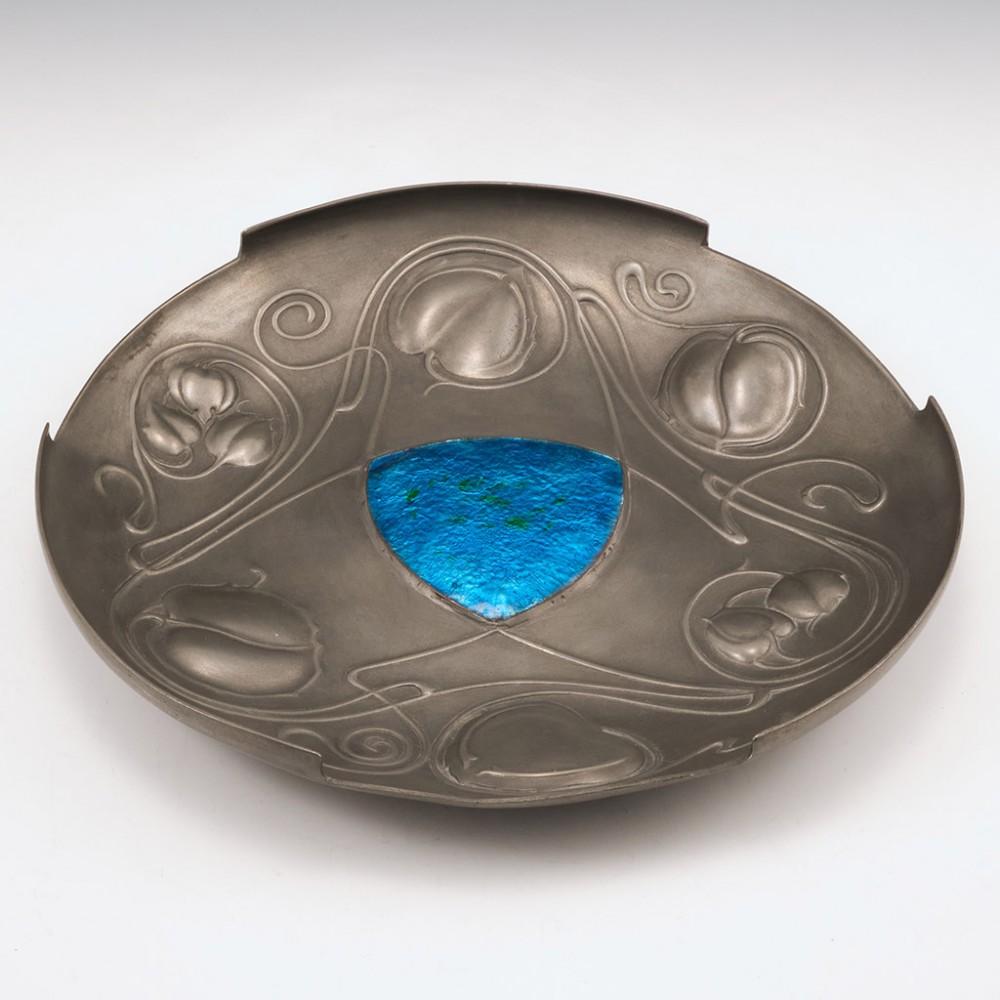 A Pewter and Enamel Bollelin Dish Designed by Archibald Knox, c1905

Additional information:
Date : Circa 1905
Period : Edward VII
Origin : Birmingham, England
Decoration :The shaped form embossed with leaves and sinuous stems around a  triangular