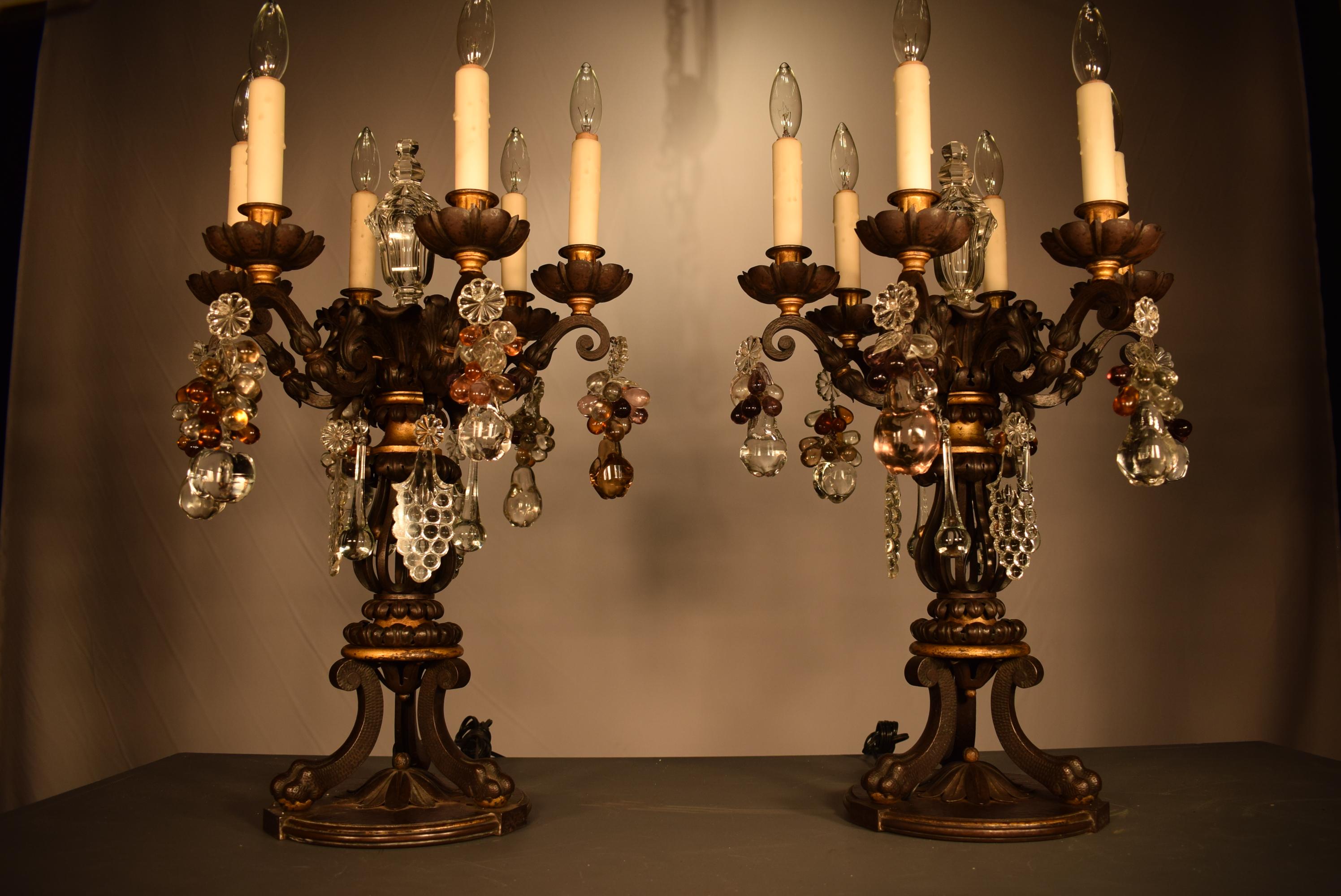 A phenomenal pair of iron girandoles, partially gilt, ornate with clusters of crystal fruits and featuring two handcut crystal pyramids. The acanthus leaves are wonderful examples of repousse technique. The rest of the body done with martele