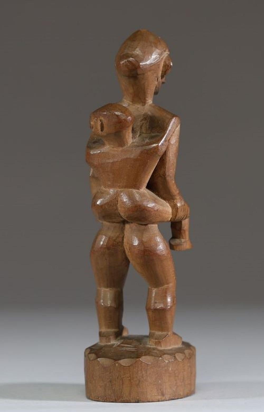 Ifugao, northern Luzon, early 20th century, a standing female figure carrying a baby on her back, the head abstracted in typical Ifugao style
Tribal patina
Height 18.5 cm