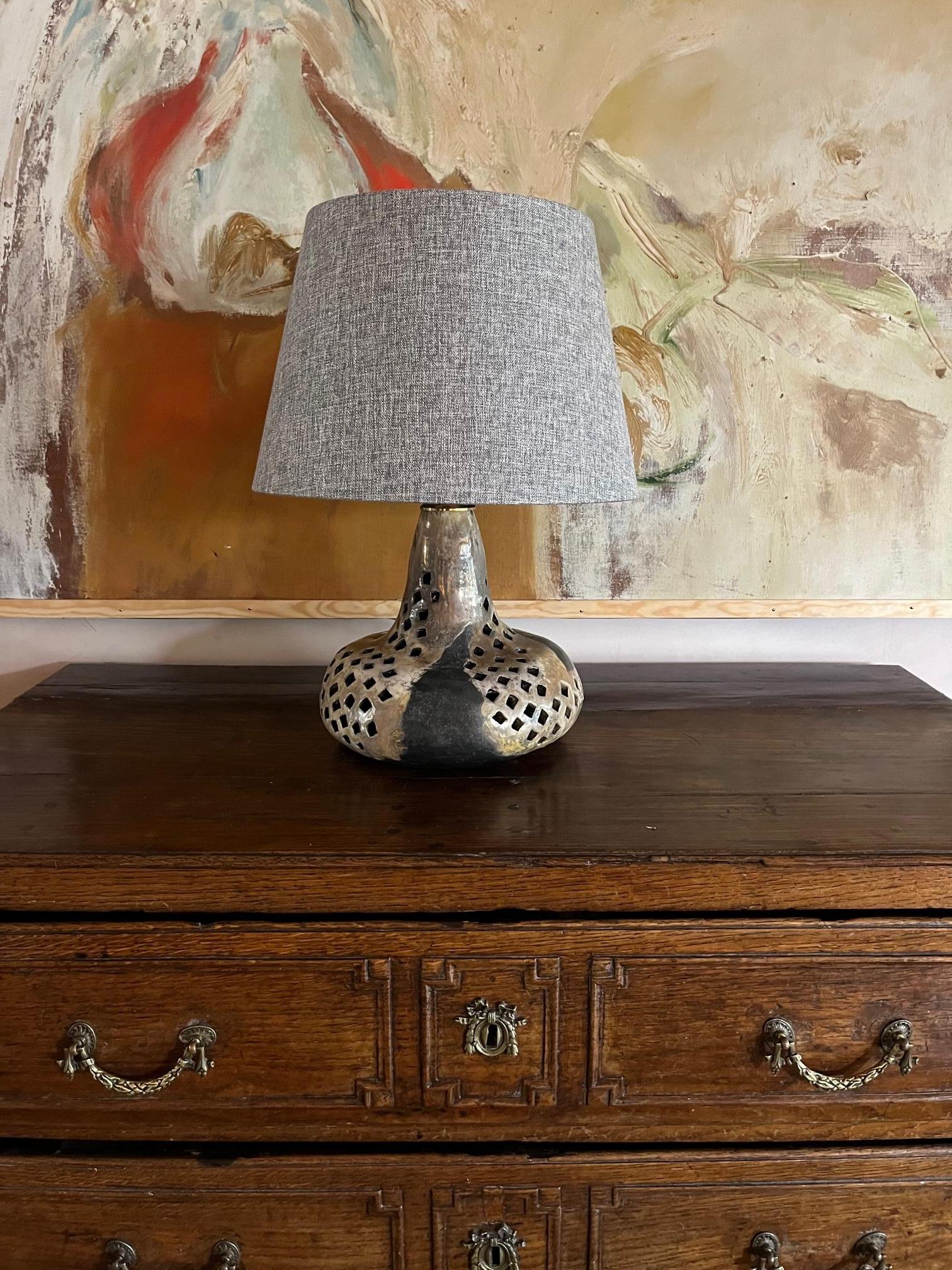 A really fabulous glazed pierced ceramic table lamp with illuminating interior. Heavy with muted abstract colours and great stand alone piece. With the shade the lamp height is 55cm. The lamp has been rewired for the UK market but can be wired for