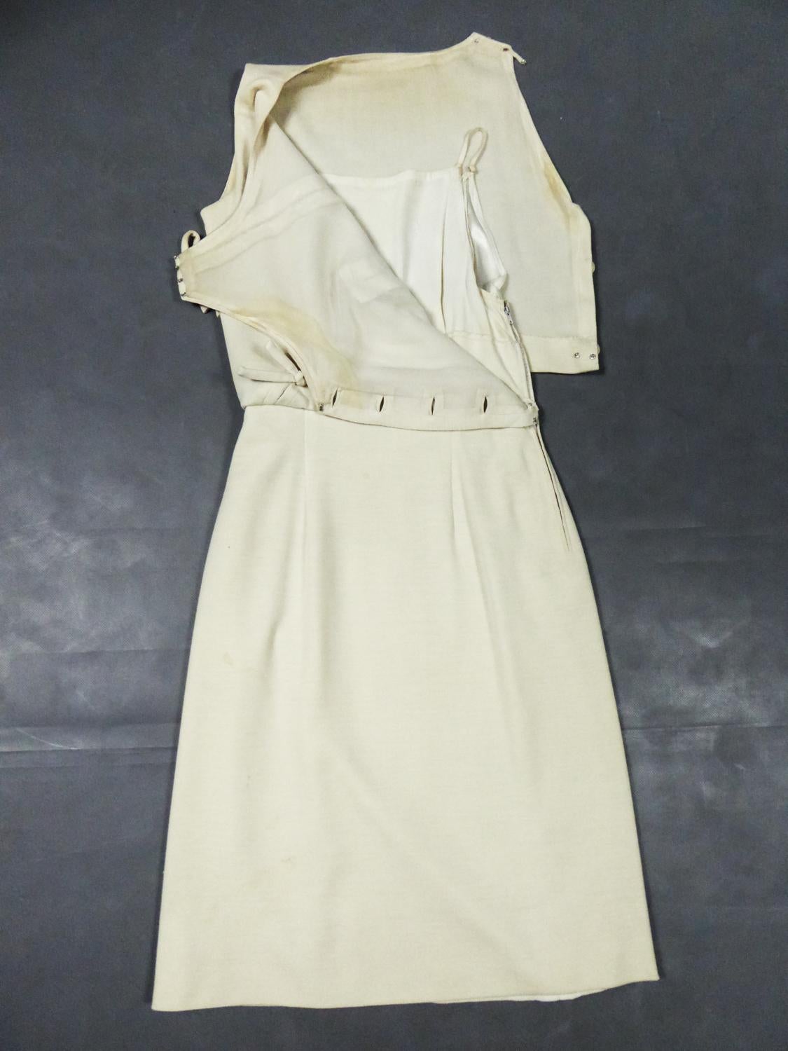 Spring Summer 1963
France

A Pierre Balmain dress in cream wool jersey from the 1960s. Sleeveless dress with straight cut tightened at the waist with loose effect. At the front, there are two similar knots and two slits stitched in bias to create a