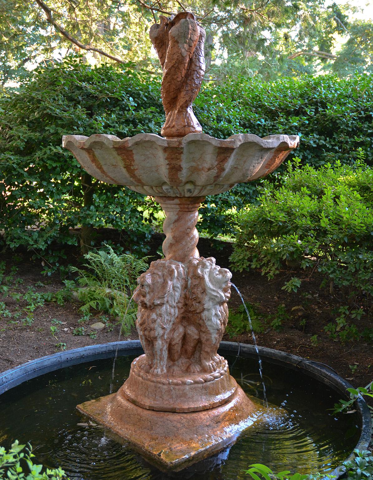 A very fine and large fountain carved of Rosso Verona marble from Italy, in the neo-classical style, with a wide waveform bowl supporting three intertwined piped dolphins, the whole resting on a turned baluster with three seated maned lions, with