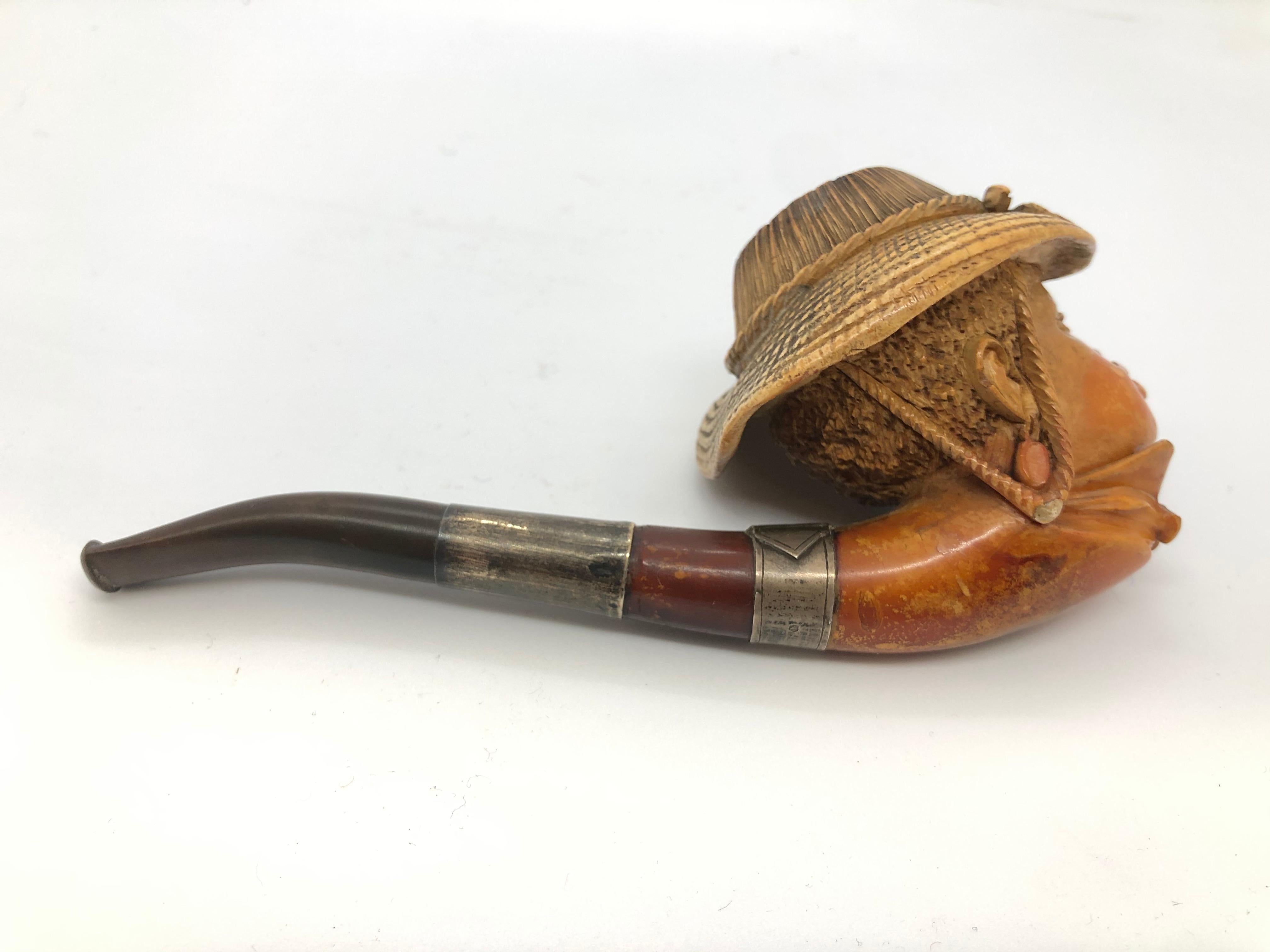 A nicely carved pipe in the shape of a mans head. Mountings of silver, one in a shape of a belt.