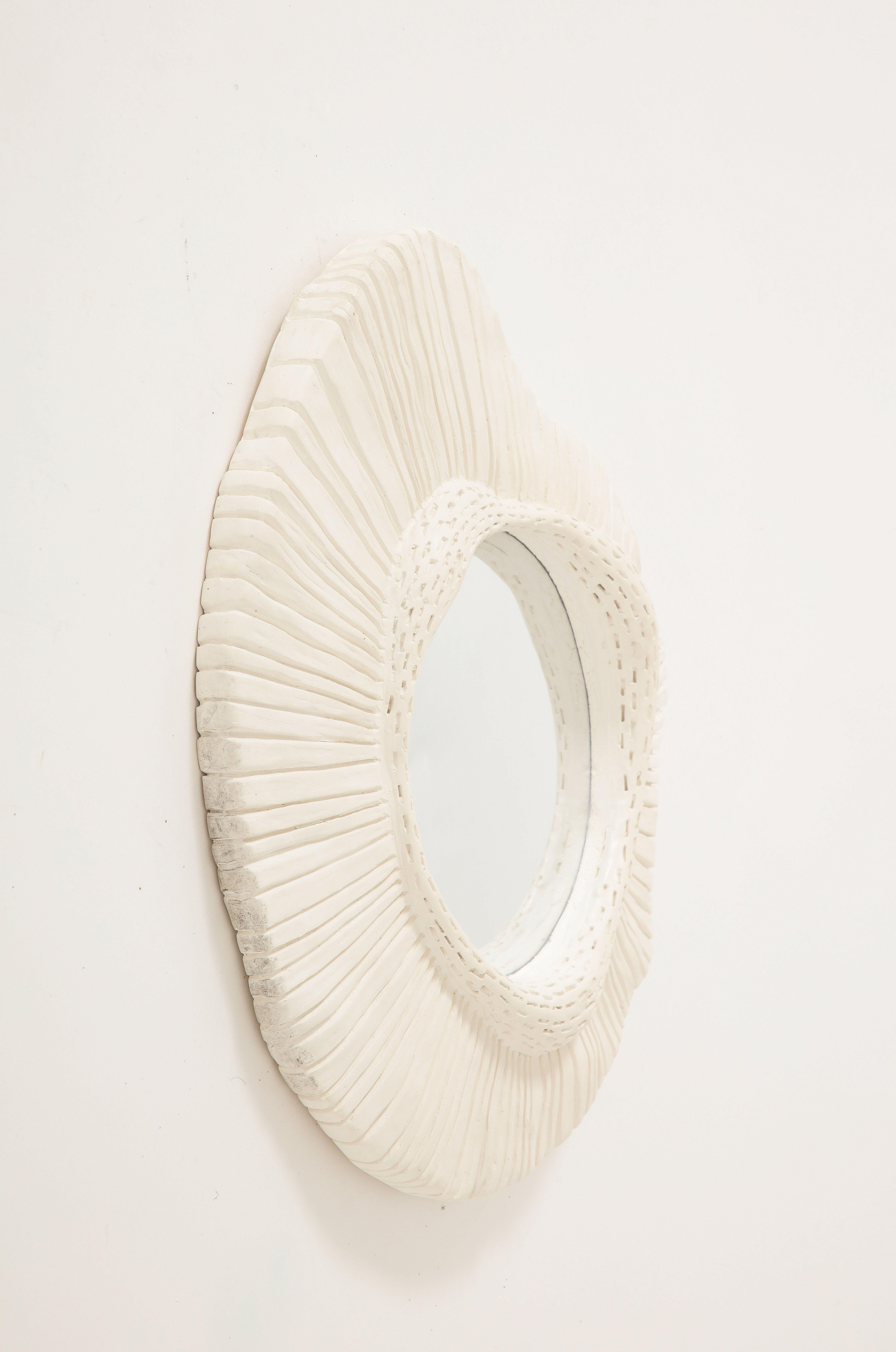 Faisant partie d'une série de notre inventaire, ce miroir en plâtre sculpté avec verre convexe est éblouissant seul ou dans le cadre d'une collection. Sa forme asymétrique et sa texture intéressante en font une pièce unique, adaptée à un