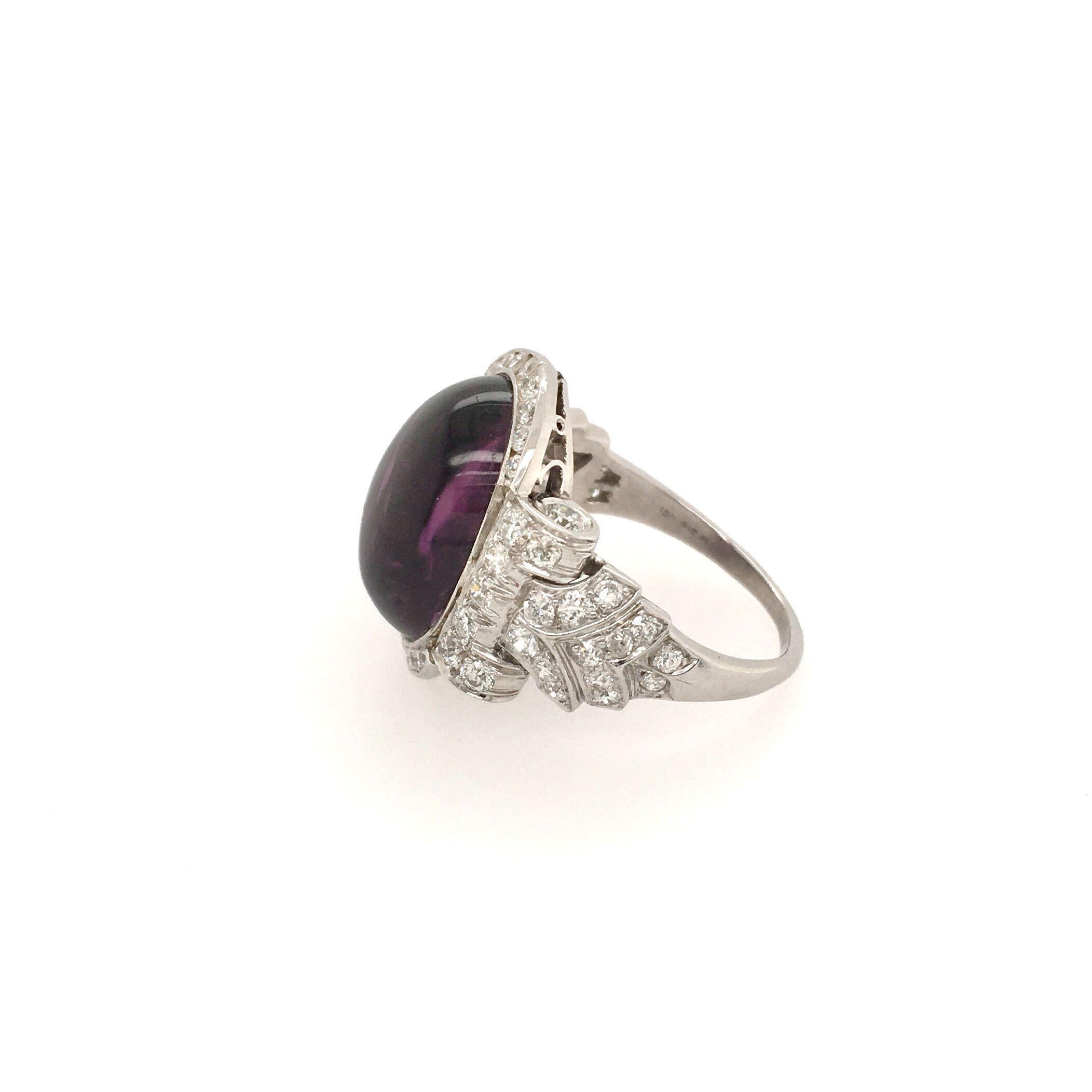A platinum, diamond and amethyst ring. Of pave diamond scrolling design, set with a cabochon amethyst measuring approximately 16.50 x 13.0mm. Fifty six (56) diamonds weigh approximately 1.40 carat. Size 8 1/4, gross weight is approximately 9.6