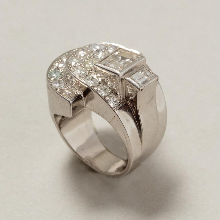 An impressive platinum Art Deco ring in a geometric shape set different cut diamonds, one step cut in the middle (1.5 carat I, Vvs) and a slightly smaller step cut next to it (0.5 H, Vvs) and with on the opposite side two half circles set with Swiss