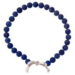 A platinum bow with diamonds on a lapis bead necklace