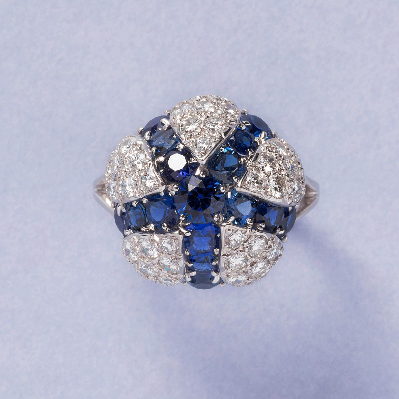 A platinum ring with a large open flower or coral anemone pavé set brilliant cut diamonds (app. 1.5 carat G-H, VS in total) with a star of brilliant cut sapphires (app. 4.95 carat in total) in between, signed: Cartier and numbered, circa