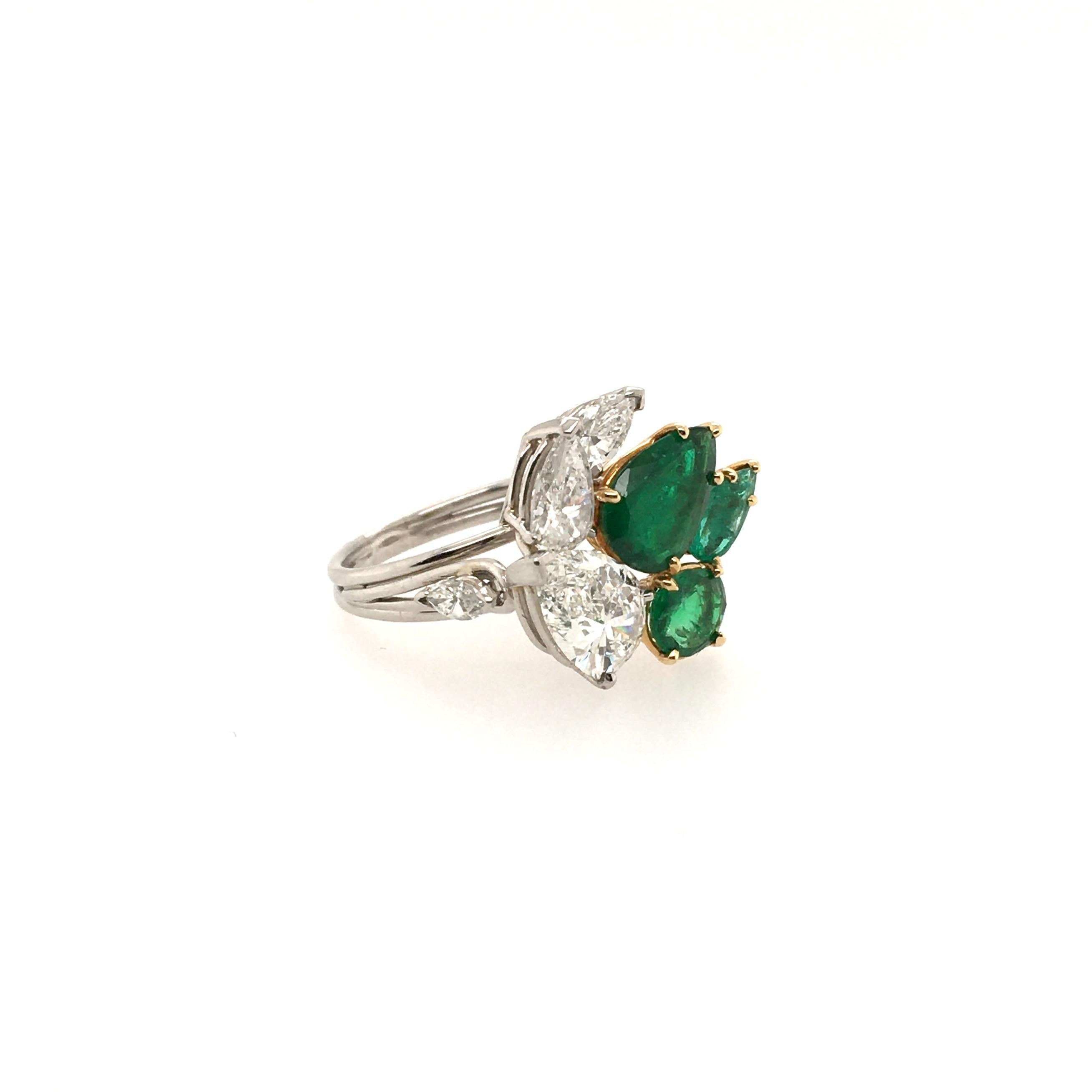 A platinum, emerald and diamond ring. Circa 1950. Designed as a cluster of pear and oval cut diamonds and emeralds. Three (3) pear shaped diamonds, two (2) pear shaped and one (1) oval cut diamond. The largest diamond weighs 1.60 carats, remaining