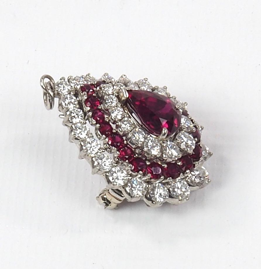 A stunning platinum, ruby and diamond pendant brooch of teardrop form consisting of a central ruby of 3.45 carats surrounded with a further 20 rubies of 1.5 carat. The piece is further set with two rows of brilliant cut diamonds of 3.5 carats.   All