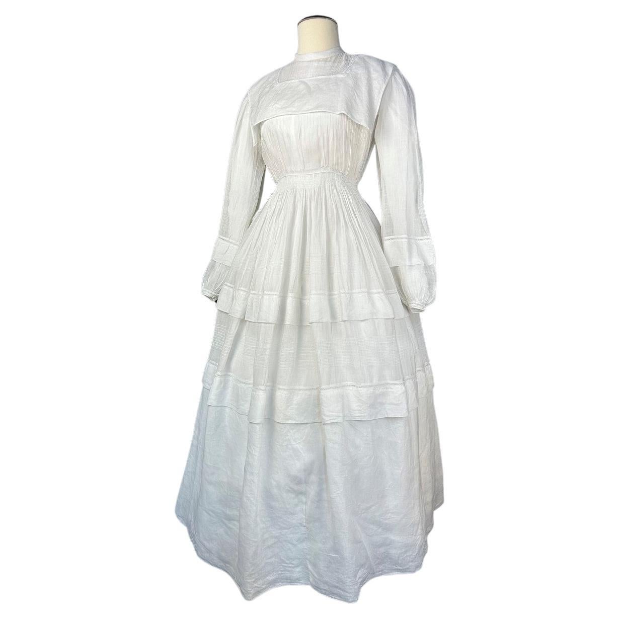 Circa 1855
France or Europe
Precious white cotton muslin or organza round crinoline walker dress dating from the beginning of the Second Empire. Dress with puffed sleeves, folded pleats and closed in the back with small mother-of-pearl buttons. Very