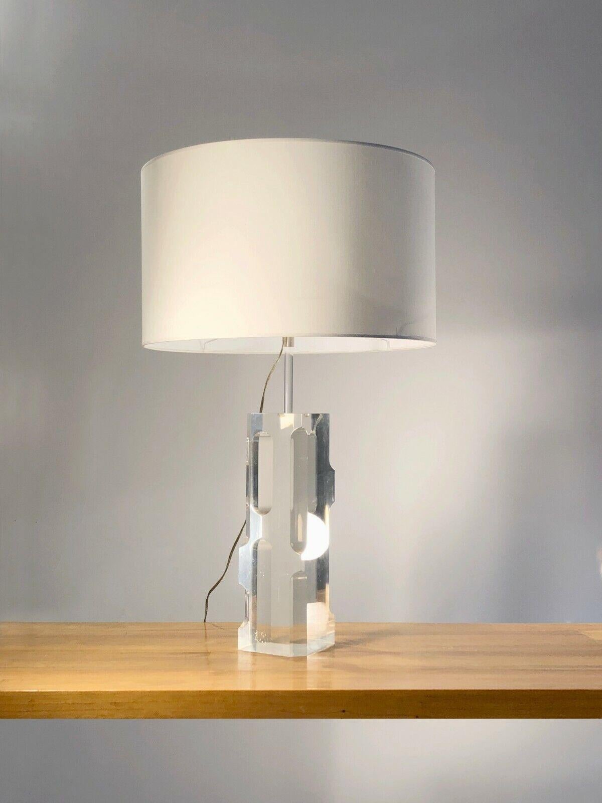 An exceptional and sculptural table lamp in prism, Post-Modernist, Seventies, Kinetic, Pop, body in a rectangular block of solid plexiglass with curved cut sides, forming a kind of prism reflecting light and reflections of the environment, by