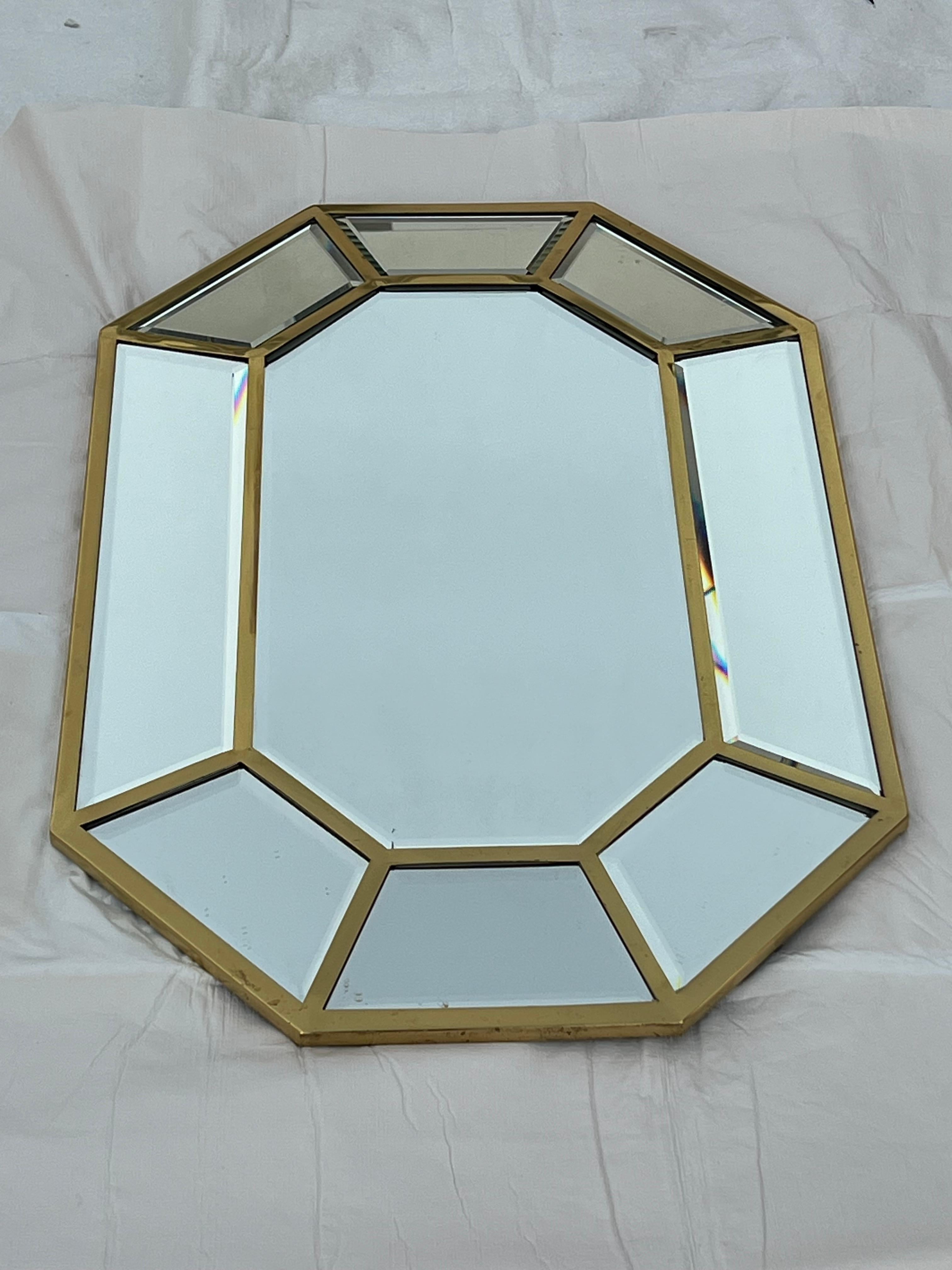 Un miroir intéressant, datant des années 1970, fabriqué par Decorative Arts. Cadre octogonal en laiton poli, avec inserts en verre segmenté et biseauté. S'étend à environ 1,5