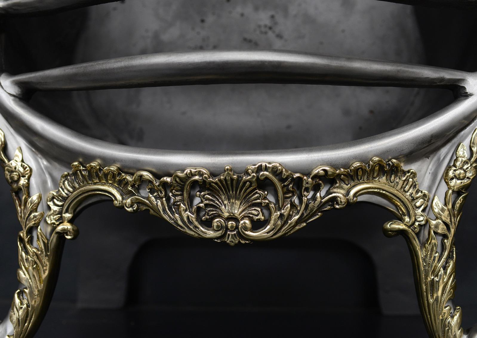 A Regency style polished steel and brass firebasket. The ornate cast brass enrichments to base with shaped front and brass finials. Decorative cast iron back behind. English, 20th century.

Width At Front:	565 mm      	22 ¼