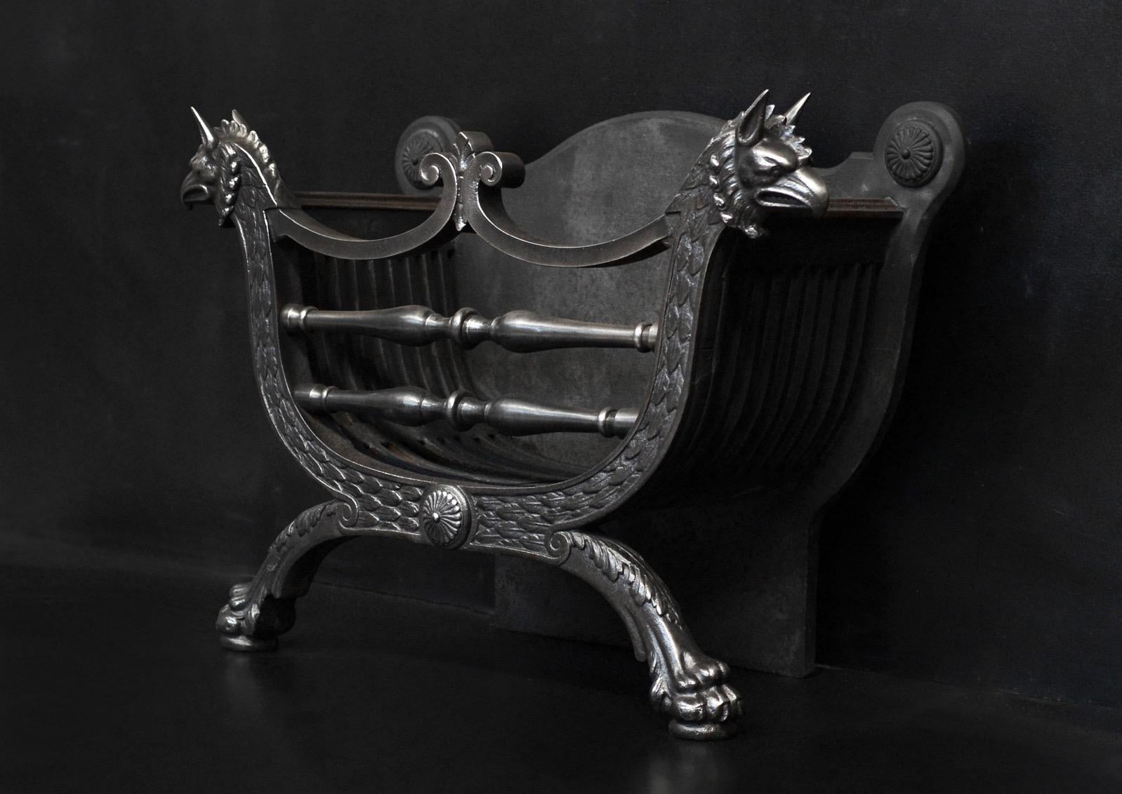 A polished cast iron firegrate. The arched base with feathers cast throughout, rosette to centre and lion's paw feet below. The burning area with shaped front bars and fleur-de-lys, flanked by cast griffin heads. Decorative cast iron fireback