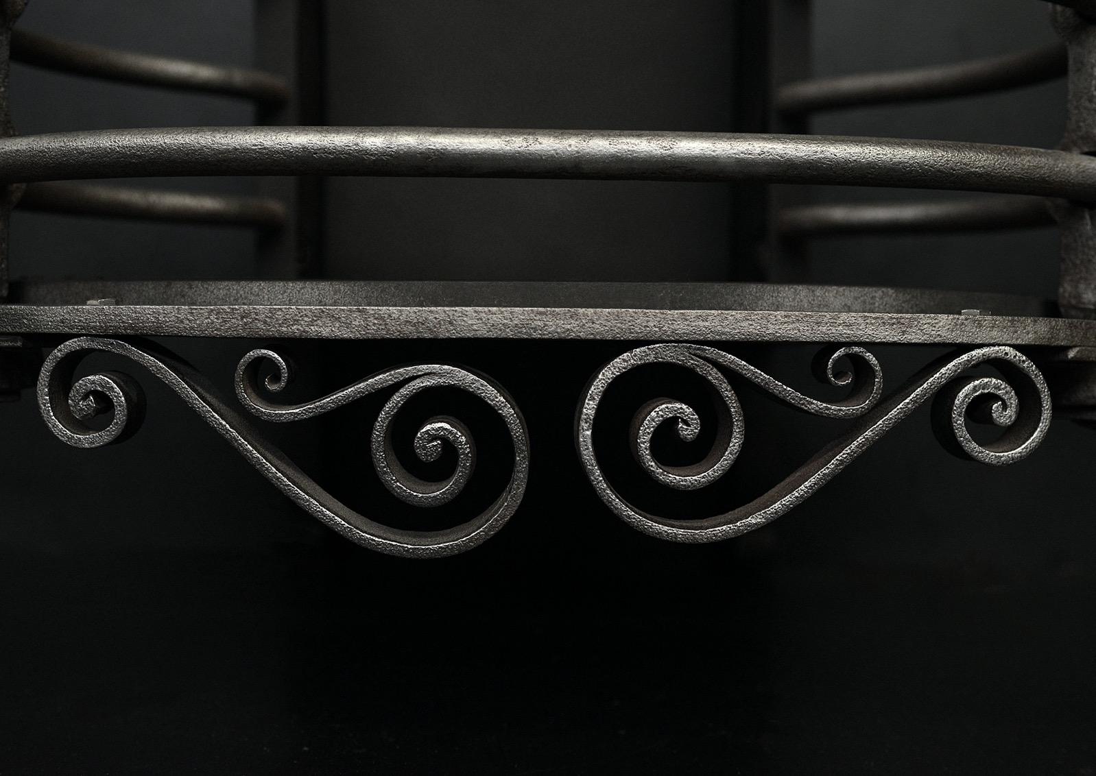 Grille de foyer en fer poli de style Arts and Crafts. La frette à volutes est flanquée de pieds en forme, avec des barres frontales arquées au-dessus. Plaque de fond unie à l'arrière, avec des volutes et des fleurons polis classiques. Anglais,