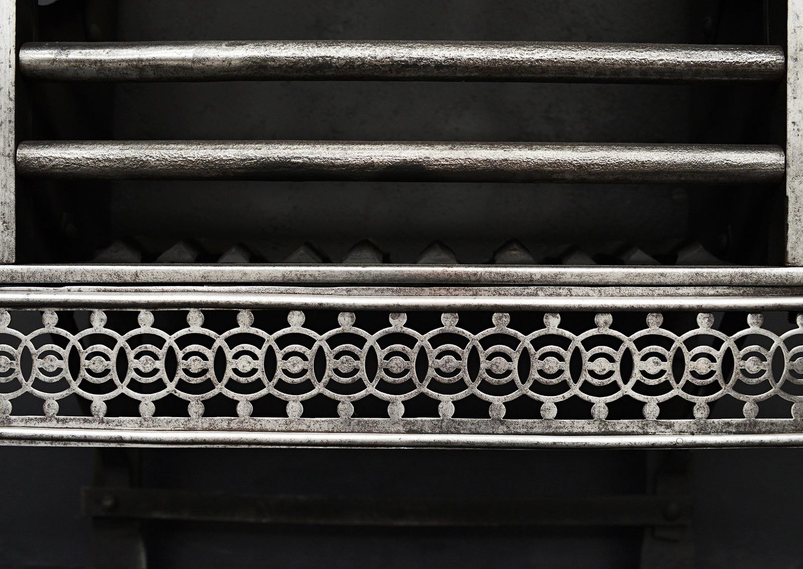 An English polished steel fire grate. The tapering legs surmounted by classical finials, the guilloche fret surmounted by cast iron front bars and iron back behind, 19th century.

Sizes:
Width At Front:	863 mm      	34 in
Width At Back:	545 mm     