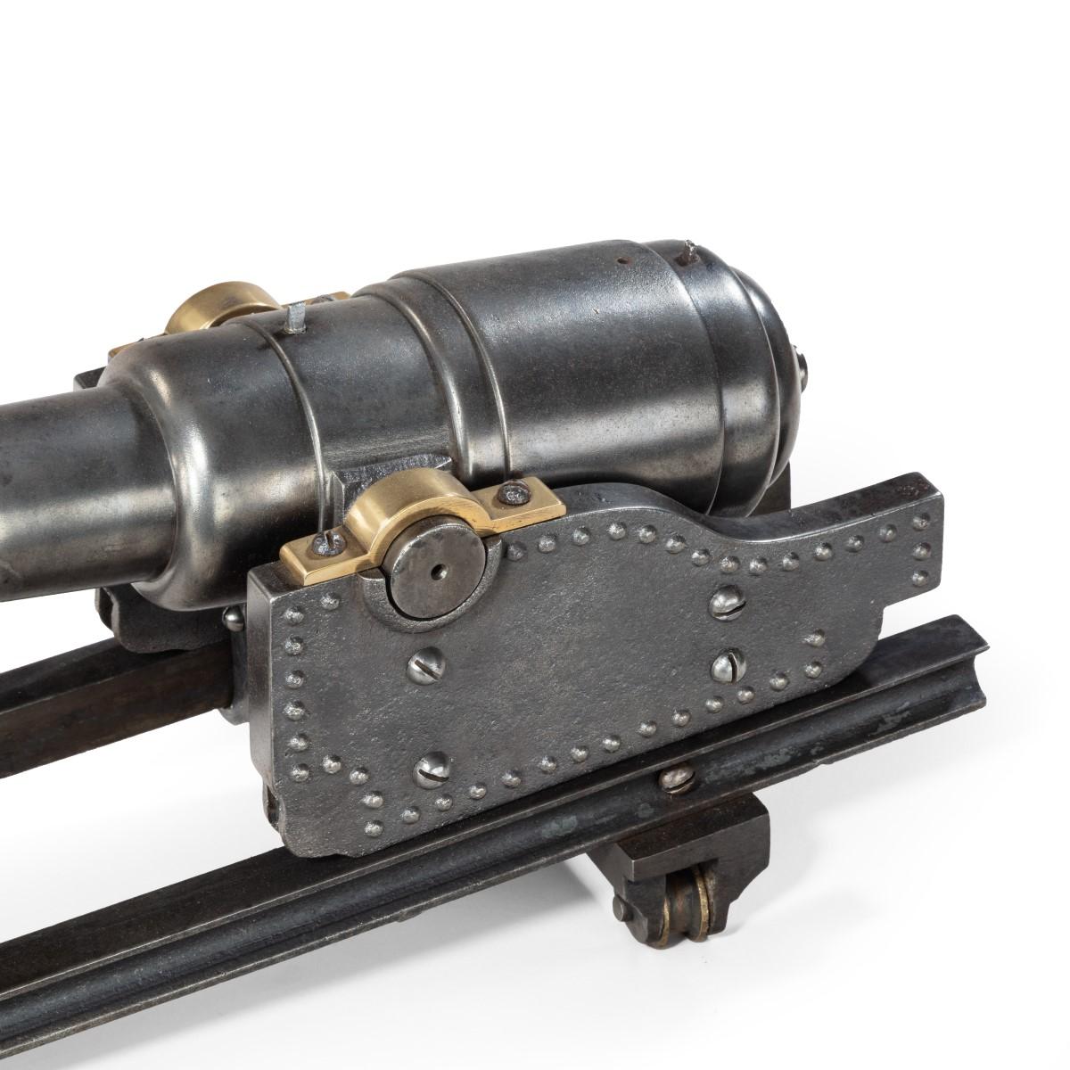 A polished steel nine stage coastal defense cannon, the barrel and riveted carriage set on sliding rails to accommodate the recoil. English, c 1900.
