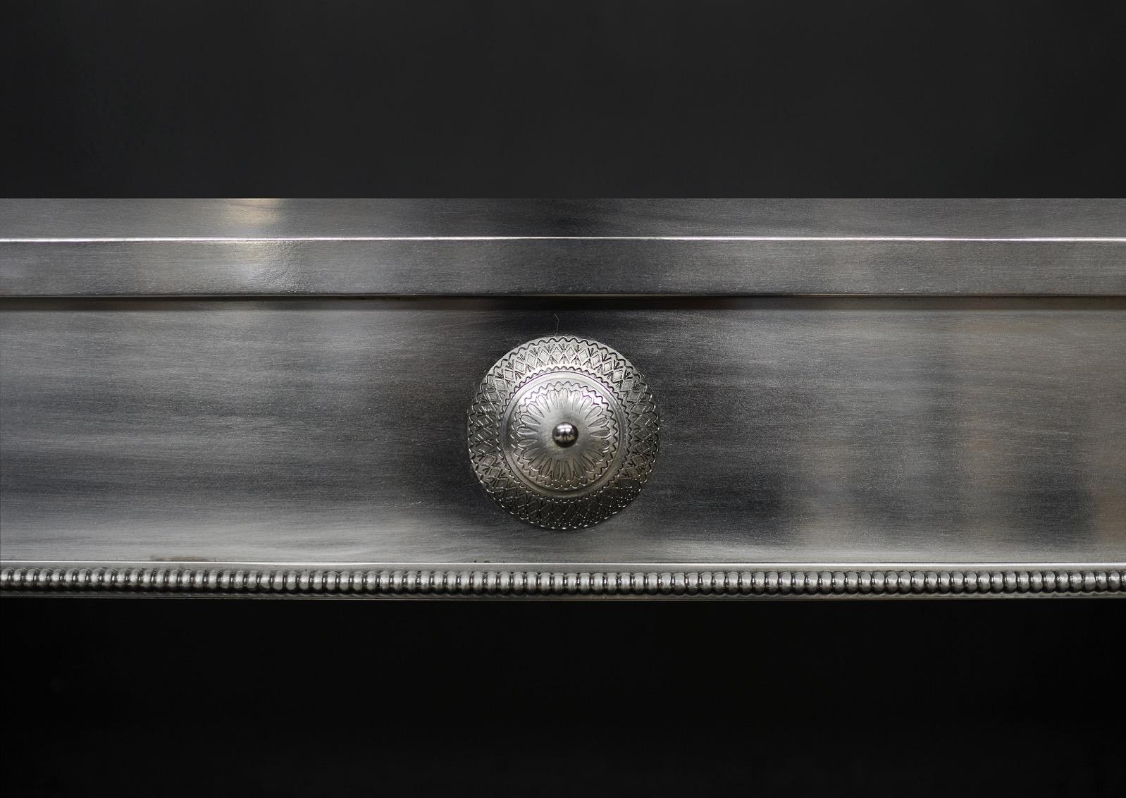 A polished steel register grate. The frame with finely engraved paterae to top and beading to inner edge. The burning area with ball finials, plain bars and fret with beading and plain paterae. English, modern. NB. May be subject to an extended lead